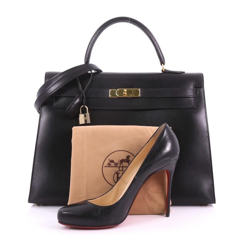 This Hermes Kelly Handbag Black Box Calf with Gold Hardware 35, crafted in black box calf leather, features single rolled top handle, protective base studs, turn lock closure and gold-tone hardware accents. Its flap opens to a black leather interior