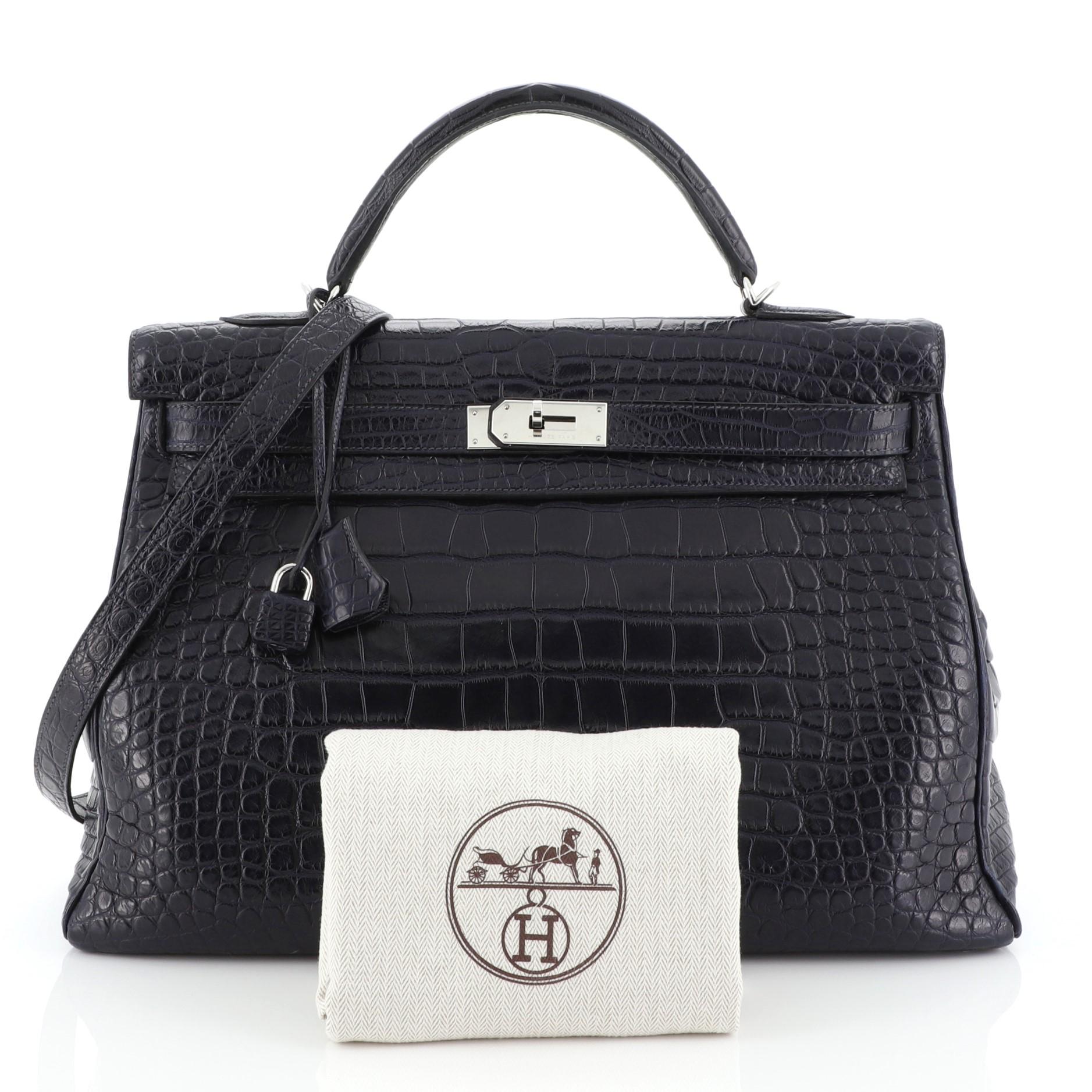 This Hermes Kelly Handbag Bleu Abysse Matte Alligator with Palladium Hardware 40, crafted in genuine Bleu Abysse blue Matte Alligator, features a single top handle, protective base studs, and palladium hardware. Its turn-lock closure opens to a Bleu