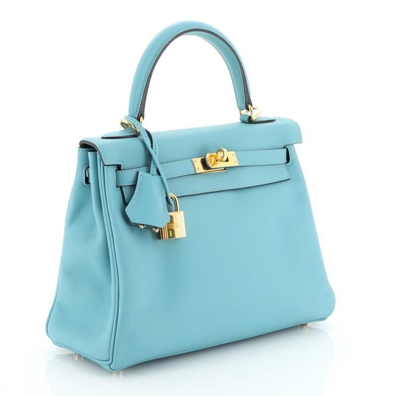 This Hermes Kelly Handbag Bleu Saint Cyr Swift with Gold Hardware 25, crafted in Bleu Saint Cyr blue Swift leather, features a single rolled top handle, frontal flap, and gold hardware. Its turn-lock closure opens to a Bleu Saint Cyr blue Swift