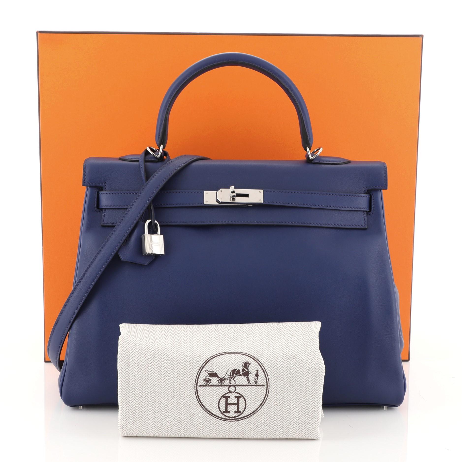 This Hermes Kelly Handbag Blue Saphir Swift with Palladium Hardware 35, crafted in Blue Saphir blue Swift leather, features a single rolled top handle, protective base studs, and palladium hardware. Its turn-lock closure opens to a Blue Saphir blue