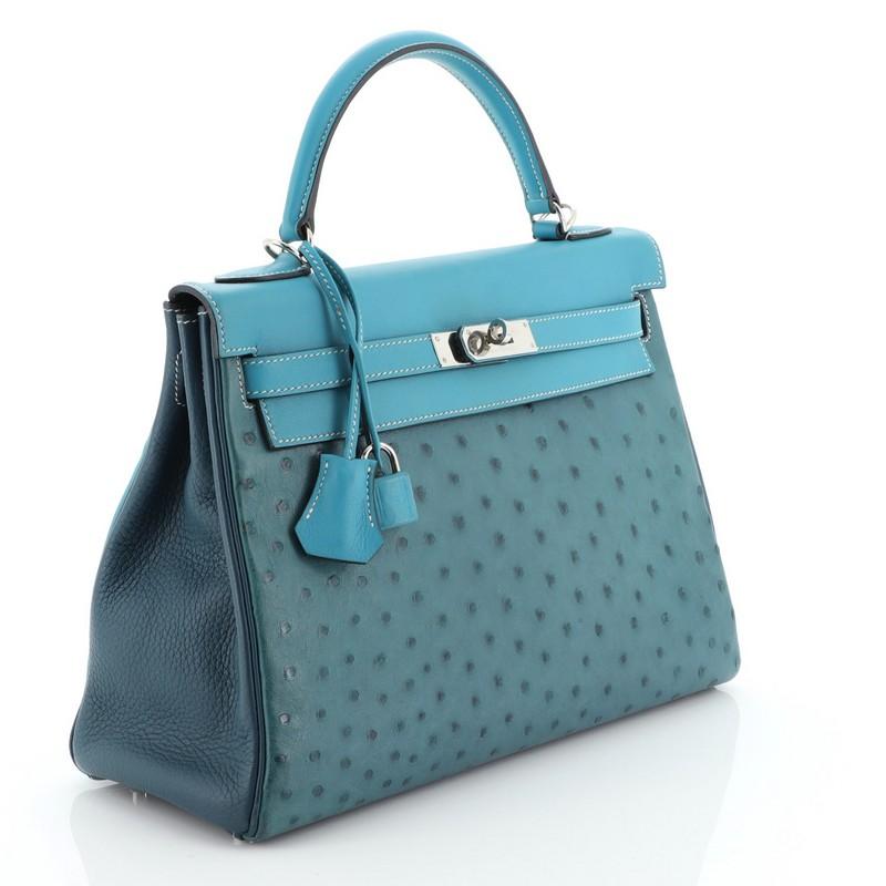 This Hermes Kelly Handbag Cobalt Ostrich and Swift with Clemence and Palladium Hardware 32, crafted in genuine Cobalt Ostrich, Colvert Clemence and Turquoise Swift leather, features a single rolled top handle, protective base studs, and Palladium