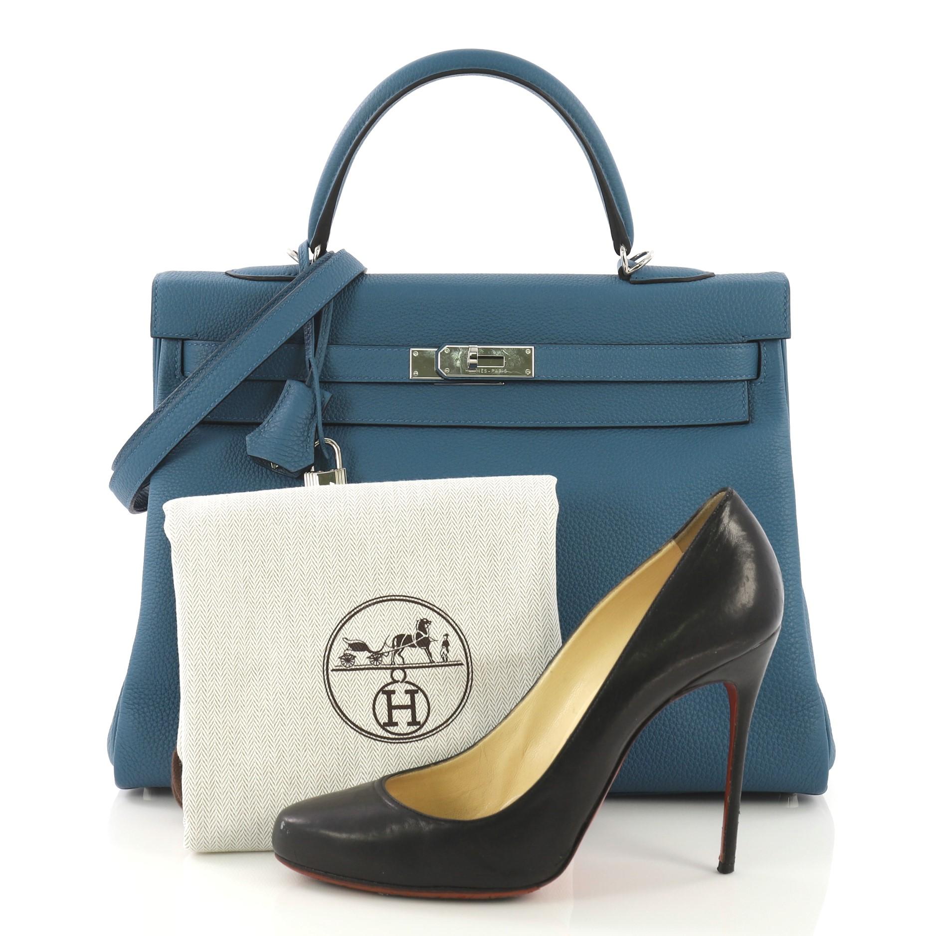 This Hermes Kelly Handbag Cobalt Togo with Palladium Hardware 35, crafted in Cobalt blue Togo leather, features a single rolled top handle, frontal flap, and palladium hardware. Its turn-lock closure opens to a Cobalt blue Chevre leather interior