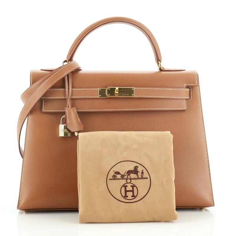This Hermes Kelly Handbag Gold Courchevel with Gold Hardware 32, crafted from Gold brown Courchevel leather, features a single top handle and gold hardware. Its turn-lock closure opens to a Gold brown Chevre leather interior with zip and slip