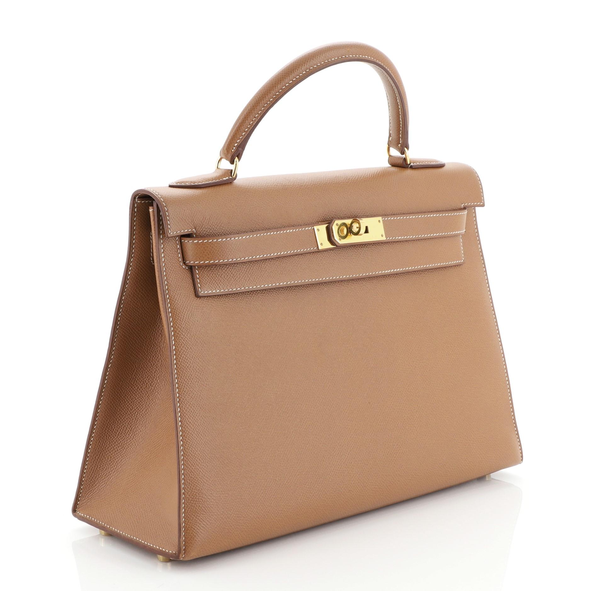 This Hermes Kelly Handbag Gold Courchevel with Gold Hardware 32 is truly a classic piece. Known for their expert craftsmanship, each bag takes over 18 hours to produce. Crafted from Gold brown Courchevel leather, this handbag features a single top