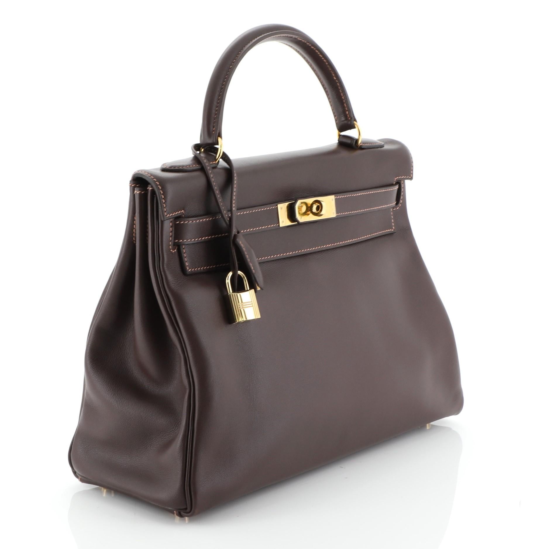 This Hermes Kelly Handbag Havane Gulliver with Gold Hardware 32, crafted in Havane brown Gulliver leather, features a single rolled top handle, protective base studs, and gold hardware. Its turn-lock closure opens to a Havane brown Gulliver leather