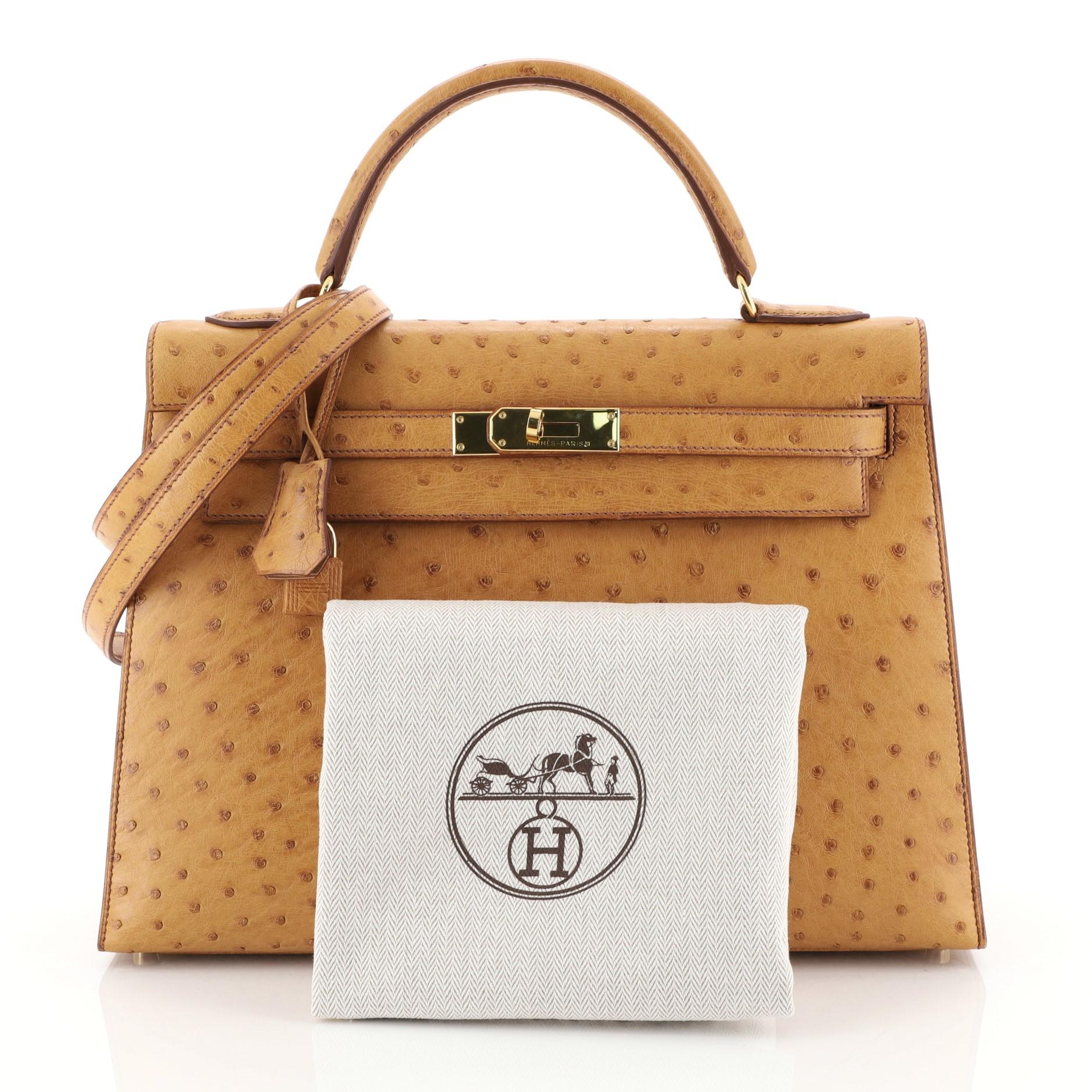 This Hermes Kelly Handbag Natural Ostrich with Gold Hardware 32, crafted from genuine Natural brown Ostrich, features a top handle, frontal flap, and gold hardware. Its turn-lock closure opens to a Natural brown Chevre leather interior with zip and