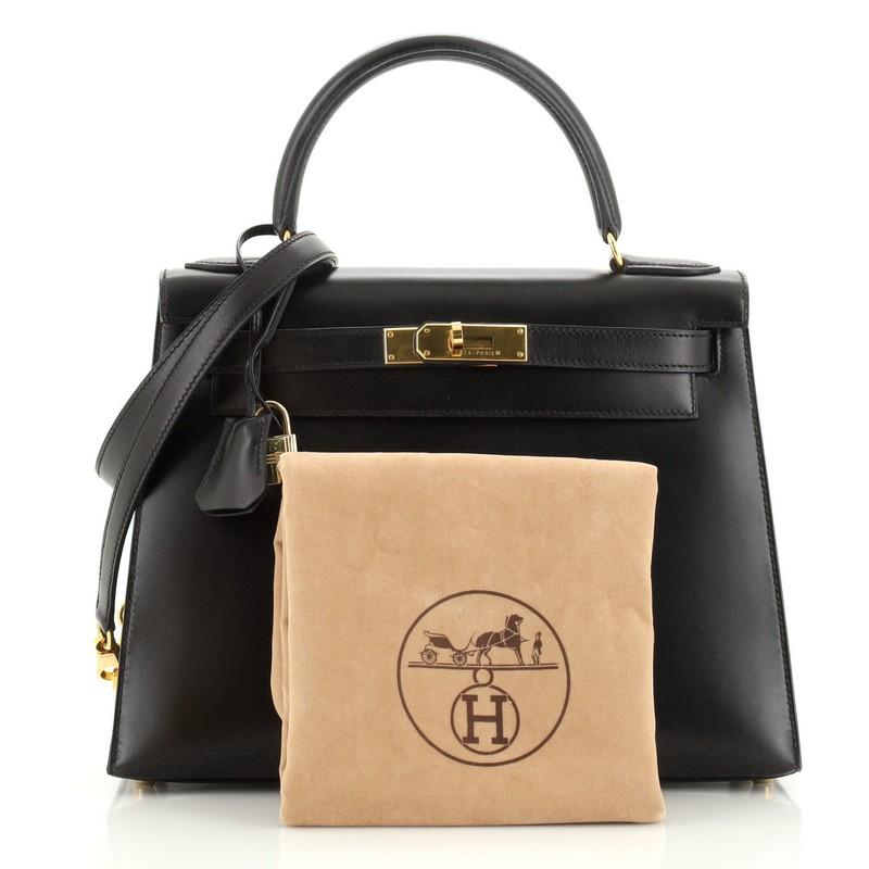 This Hermes Kelly Handbag Noir Box Calf with Gold Hardware 28, crafted in Noir black Box Calf leather, features a single top handle, frontal flap, and gold hardware. Its turn-lock closure opens to a Noir black Chevre leather interior with zip and