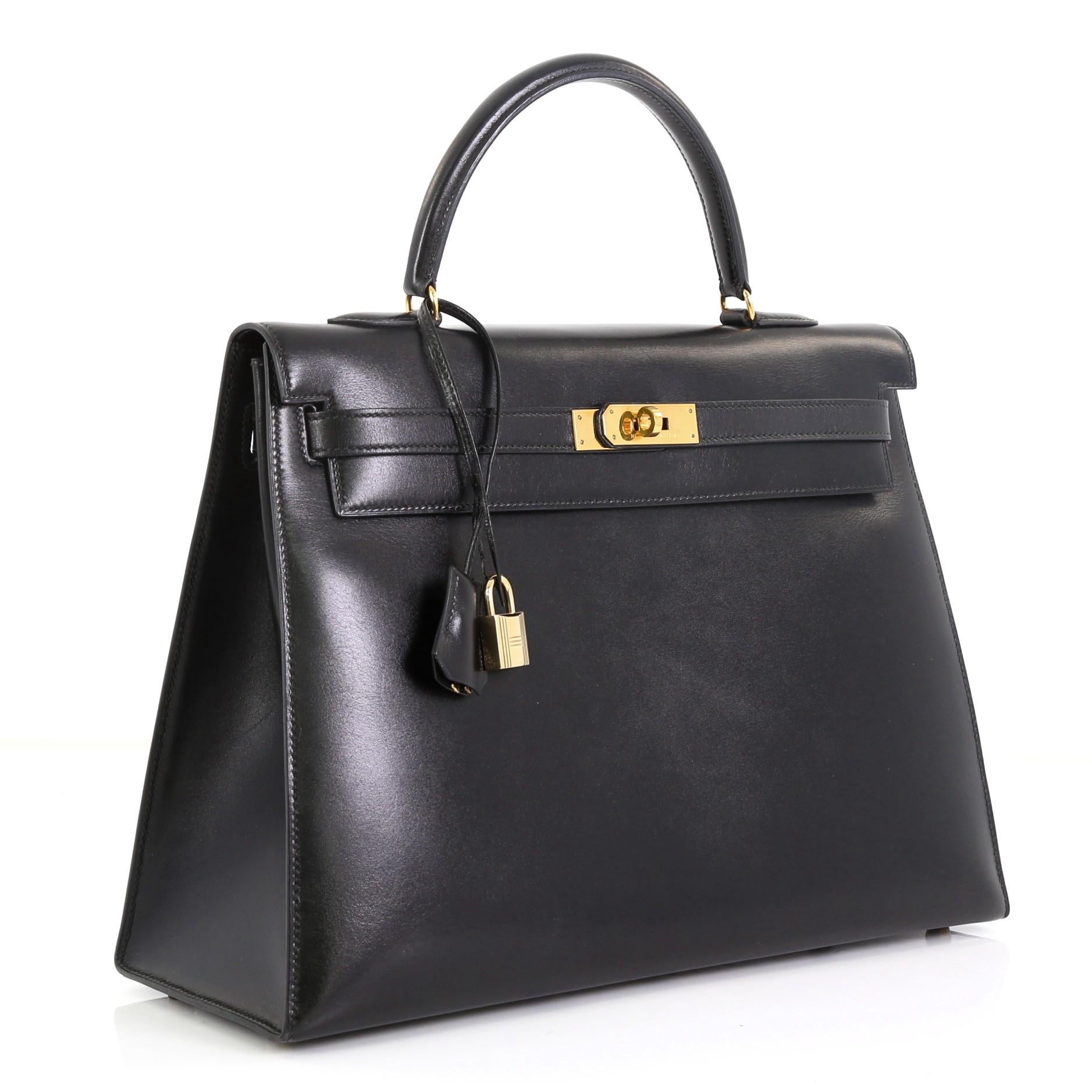 This Hermes Kelly Handbag Noir Box Calf with Gold Hardware 35, crafted from Noir black Box Calf leather, features a single top handle and gold hardware. Its turn-lock closure opens to a Noir black Chevre leather interior with zip and slip pockets.