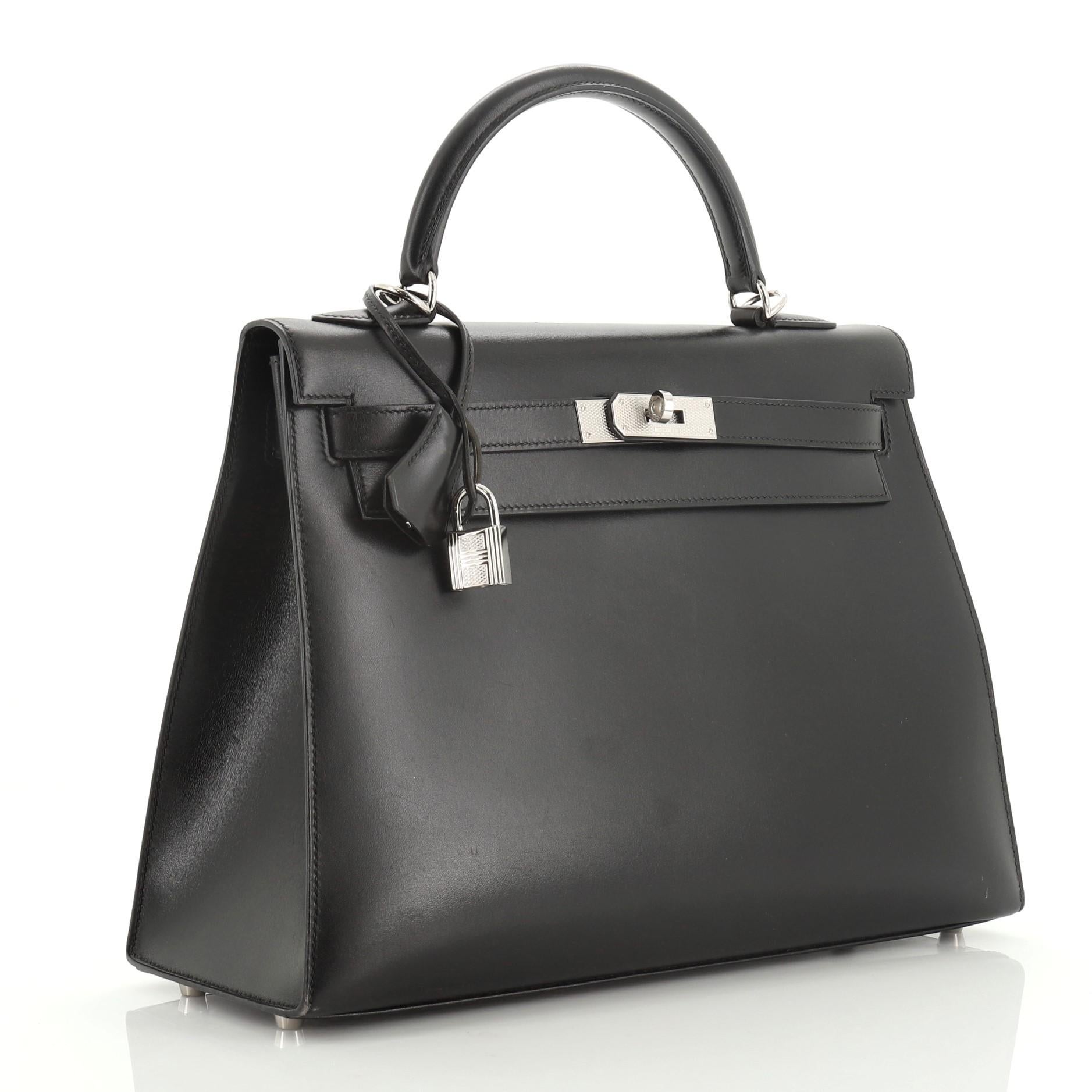 This Hermes Kelly Handbag Noir Box Calf with Guilloche Palladium Hardware 32, Crafted from Noir black Box Calf leather, this handbag features a single top handle and palladium guilloche hardware. Its turn-lock closure opens to a Noir black Chevre