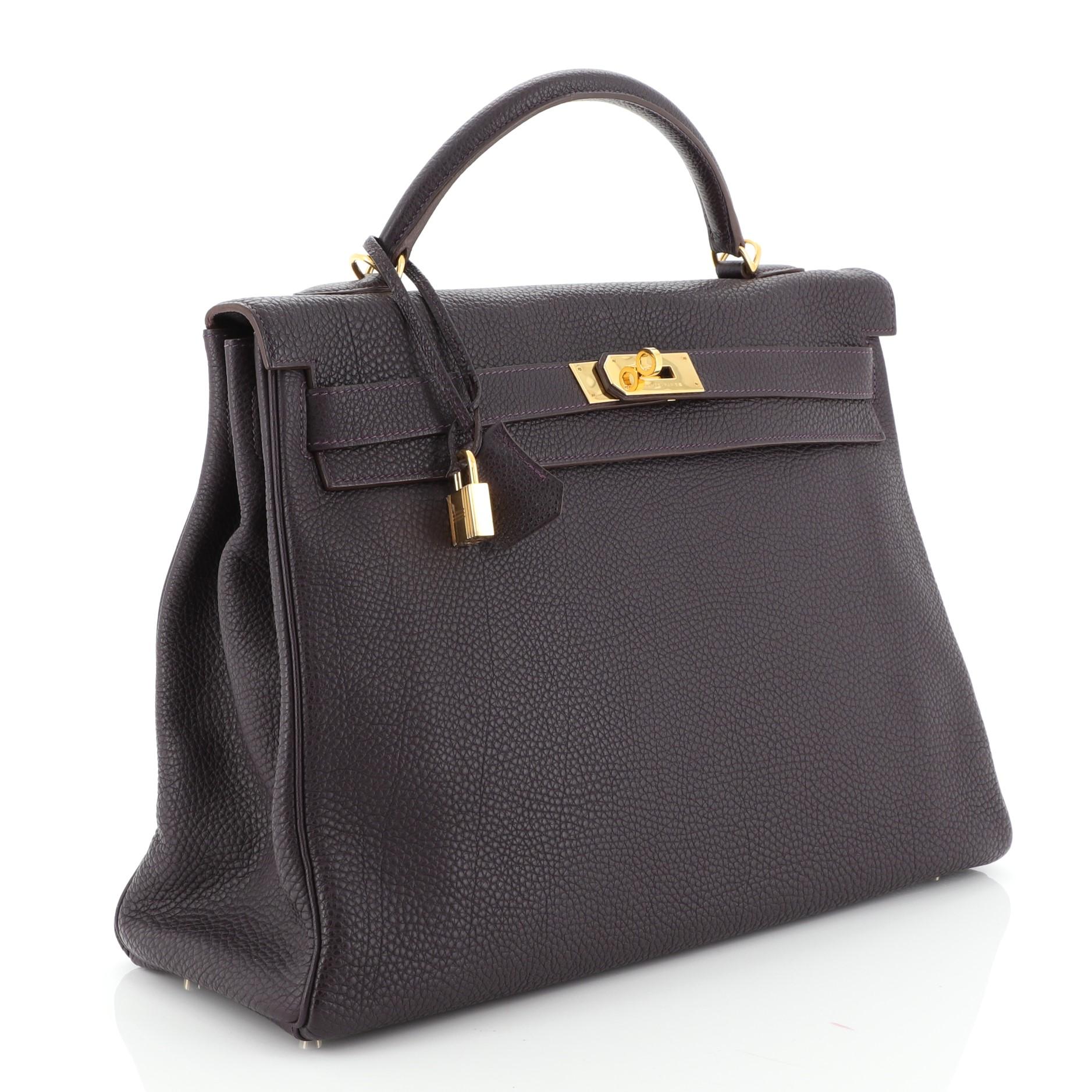 This Hermes Kelly Handbag Raisin Togo with Gold Hardware 40, crafted in Raisin purple Togo leather, features a single rolled top handle, protective base studs, and gold hardware. Its turn-lock closure opens to a Raisin purple Chevre leather interior