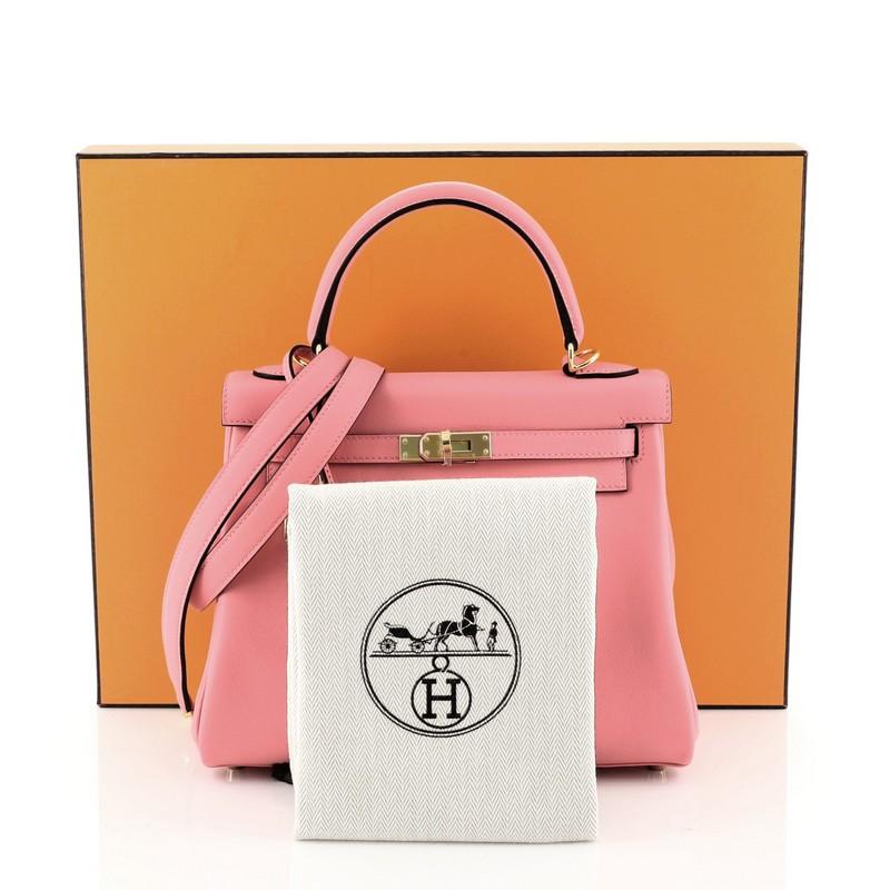 This Hermes Kelly Handbag Rose Lipstick Swift with Gold Hardware 25, crafted in Rose Lipstick pink Swift leather, features a single rolled top handle, frontal flap, and gold hardware. Its turn-lock closure opens to a Rose Lipstick pink Swift leather