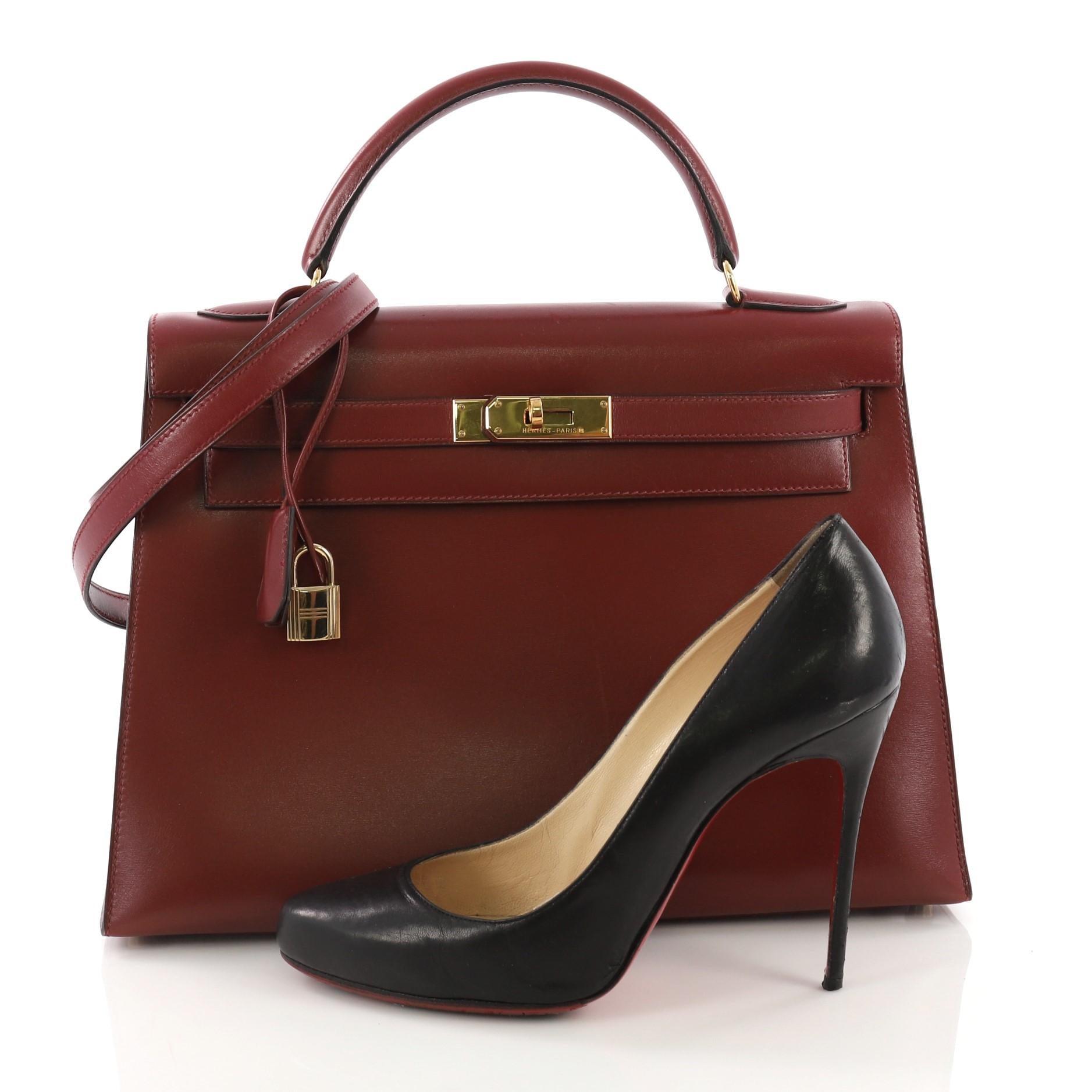 This Hermes Kelly Handbag Rouge H Box Calf with Gold Hardware 32, crafted from red Rouge H Box calf leather, features a single looped top handle, frontal flap, and gold-tone hardware. Its turn-lock closure opens to a red leather interior with zip