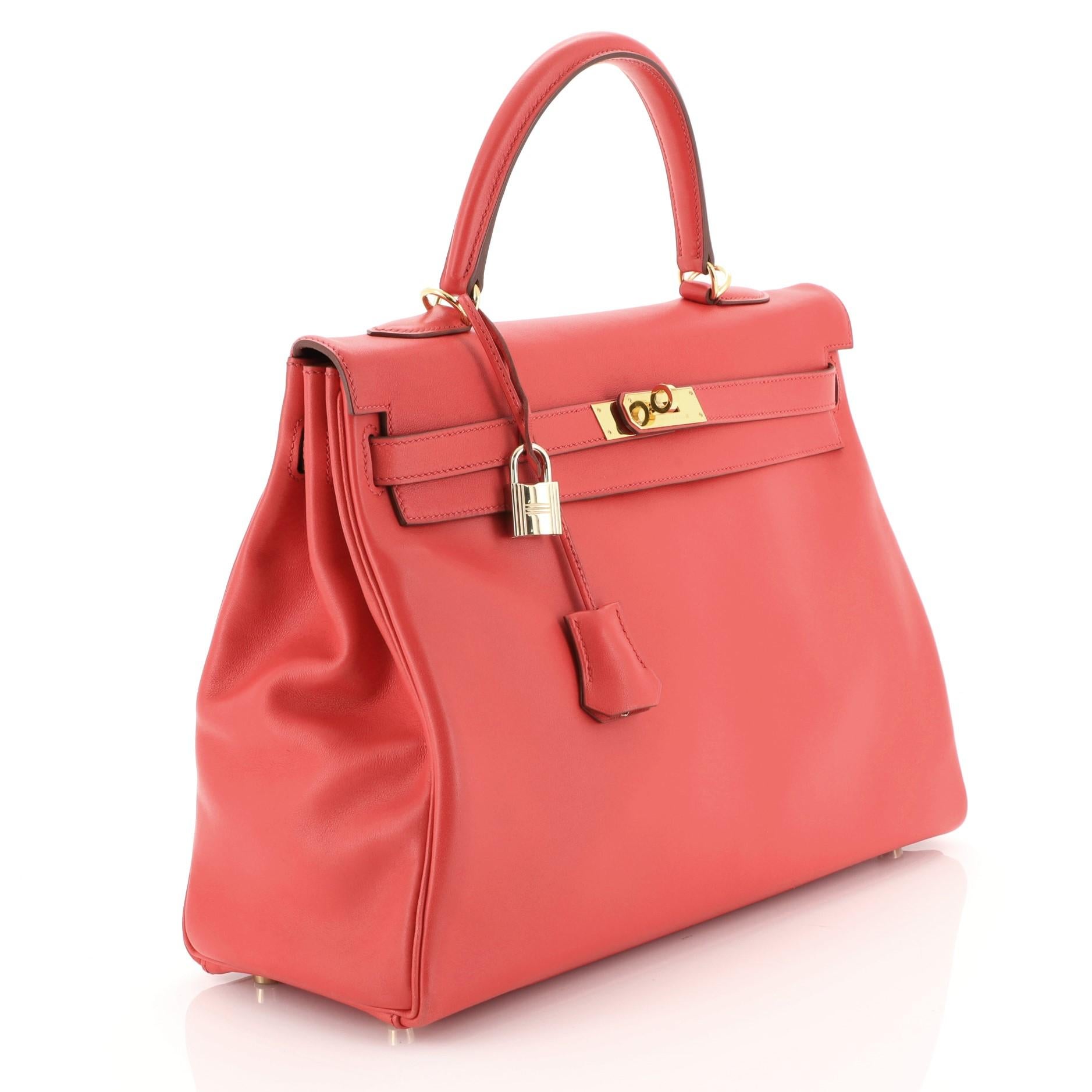 This Hermes Kelly Handbag Rouge Vif Gulliver with Gold Hardware 35, crafted in Rouge Vif red Gulliver leather, features a rolled top handle, protective base studs, and gold hardware. Its turn-lock closure opens to a Rouge Vif red Gulliver leather