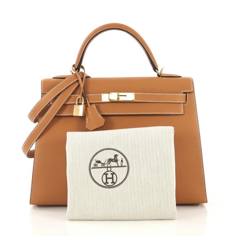 This Hermes Kelly Handbag Toffee Epsom with Gold Hardware 32, crafted from Toffee brown Epsom leather, features a single top handle and gold hardware. Its turn-lock closure opens to a Toffee brown Chevre leather interior with zip and slip pockets.