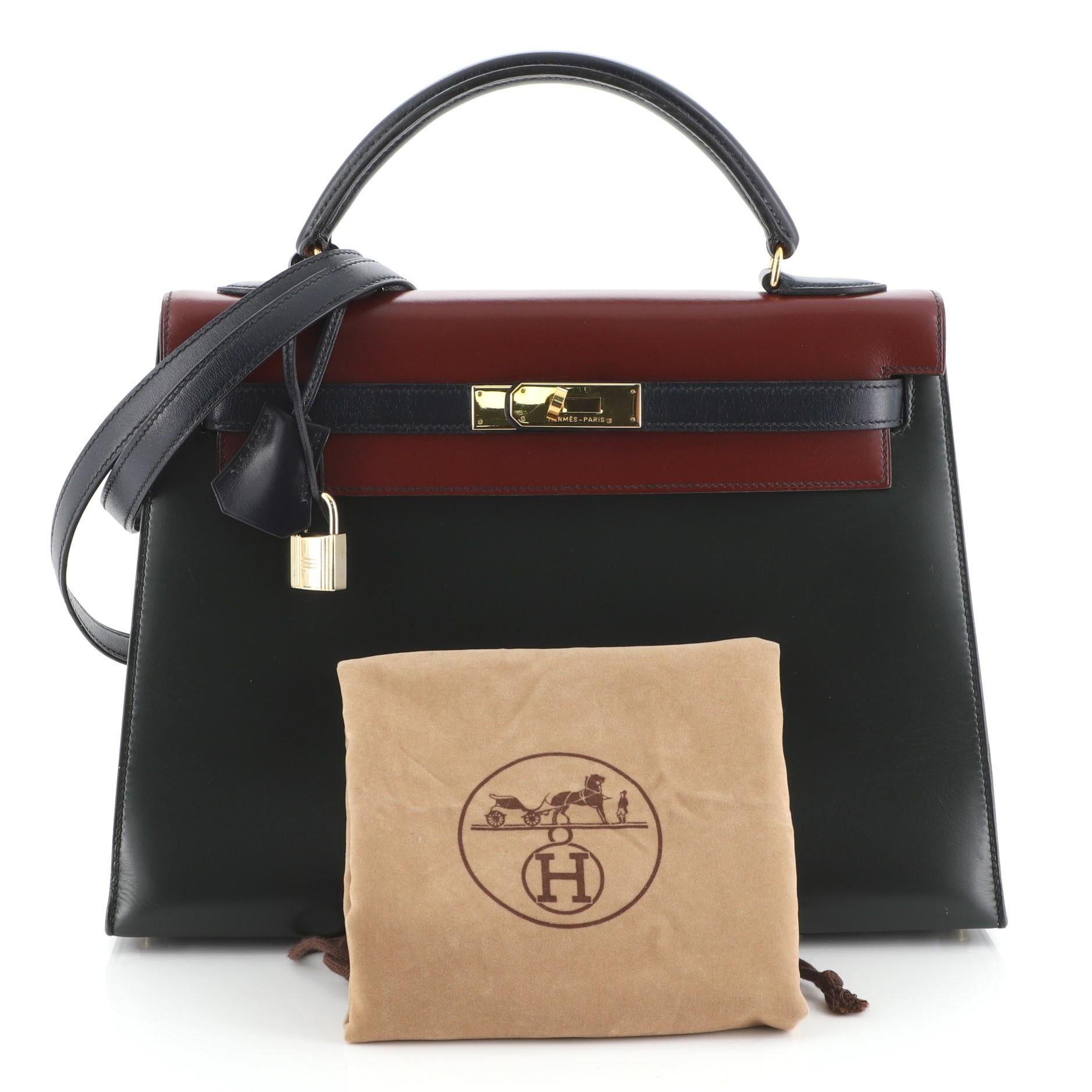 This Hermes Kelly Handbag Tricolor Box Calf with Gold Hardware 32, crafted in Rouge H red, Vert Fonce green, and Bleu Marine blue Box Calf leather, features a single top handle, protective base studs, and gold hardware. Its turn-lock closure opens