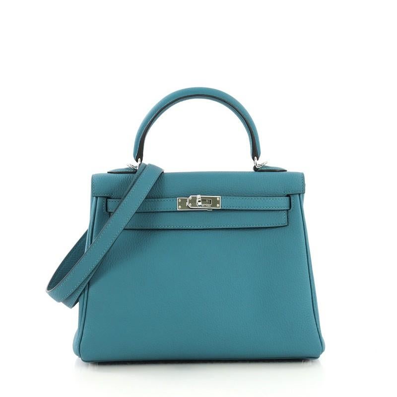 This Hermes Kelly Handbag Turquoise Togo with Palladium Hardware 25, crafted in Turquoise blue Togo leather, features a single rolled top handle, frontal flap, and palladium hardware. Its turn-lock closure opens to a Turquoise blue Chevre leather