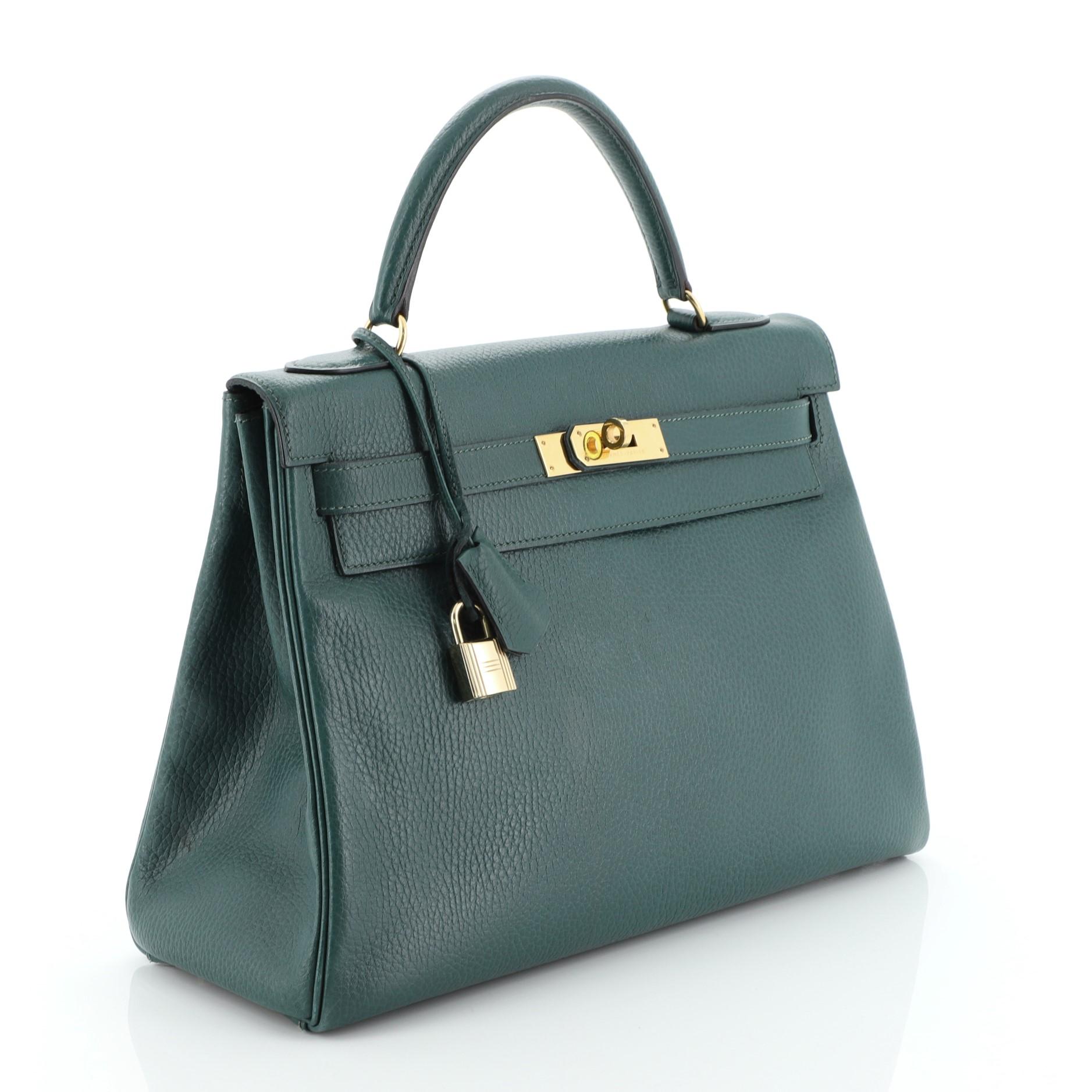 This Hermes Kelly Handbag Vert Clair Ardennes with Gold Hardware 32, crafted in Vert Clair green Ardennes leather, features a single top handle, frontal flap, and gold hardware. Its turn-lock closure opens to a Vert Fonce green Chevre leather