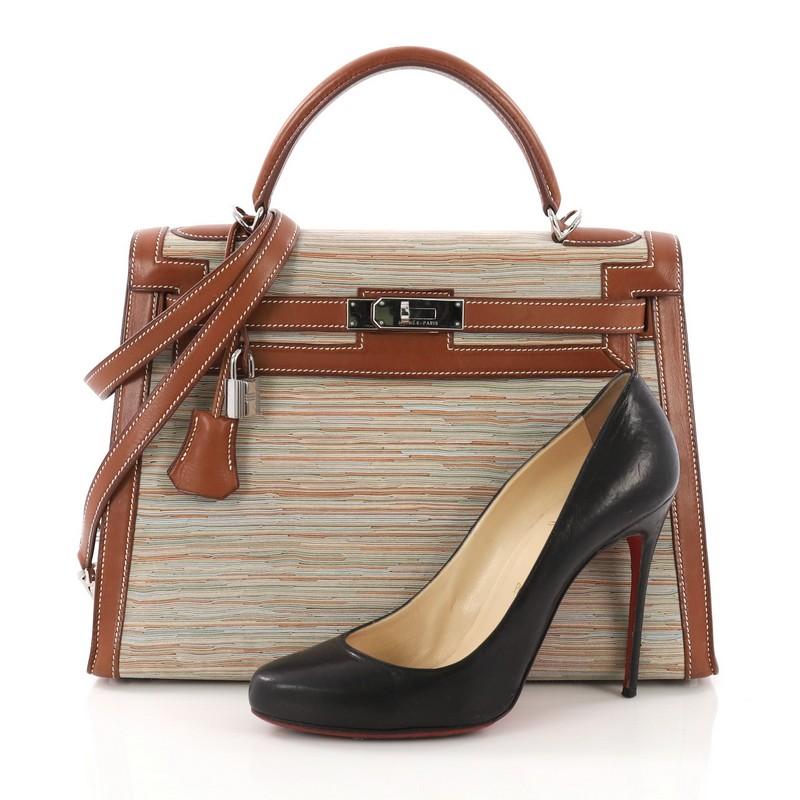 This Hermes Kelly Handbag Vibrato and Barenia 32, crafted in Multicolor Vibrato and Barenia, features a single rolled top handle, protective base studs, and palladium-tone hardware. Its turn-lock closure opens to a brown leather interior with zip