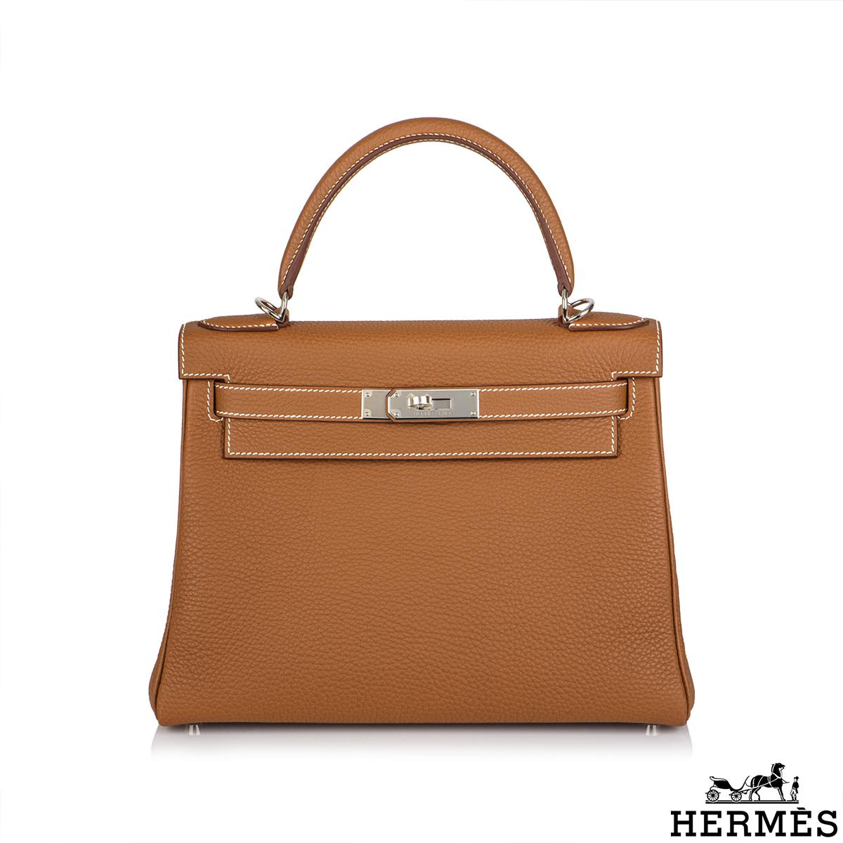 A classic Hermès Kelly II Retourne 28cm handbag. The gold togo leather bag is detailed with palladium hardware. The exterior of this Kelly features a Retourne style in togo leather. It has a front toggle closure, a single rolled handle and tonal