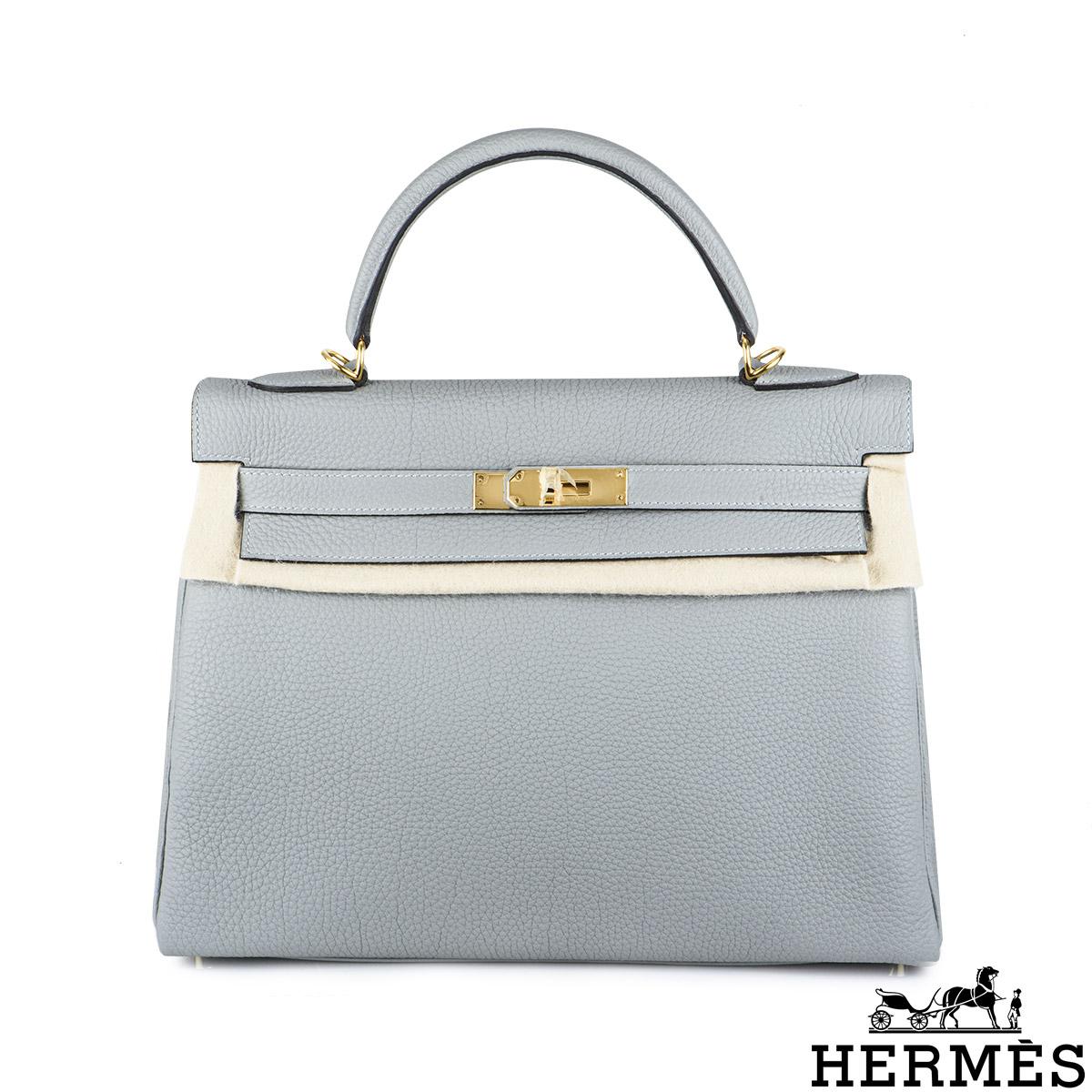 A stylish Hermès Kelly 32cm Gris Mouette handbag. The exterior of this Kelly features Gris Mouette veau togo leather with gold tone hardware. It has a front toggle closure, a single rolled handle, and tonal stitching. The interior is lined with Gris