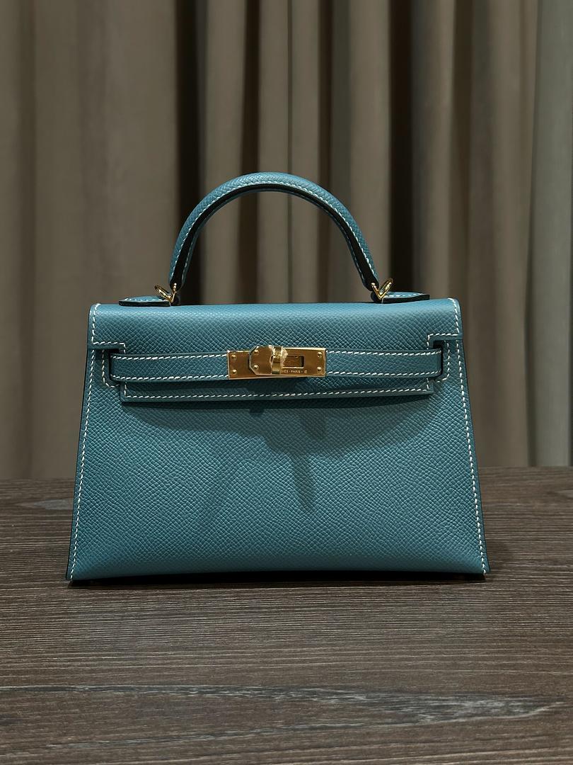 Jewels Aficionado offers an Hermès Bleu Jean Mini Kelly 20 Sellier in Epsom leather that is a refined blend of sophistication and structure. Its medium blue hue, sharp external stitching, and gold hardware create a timeless, polished look, while the