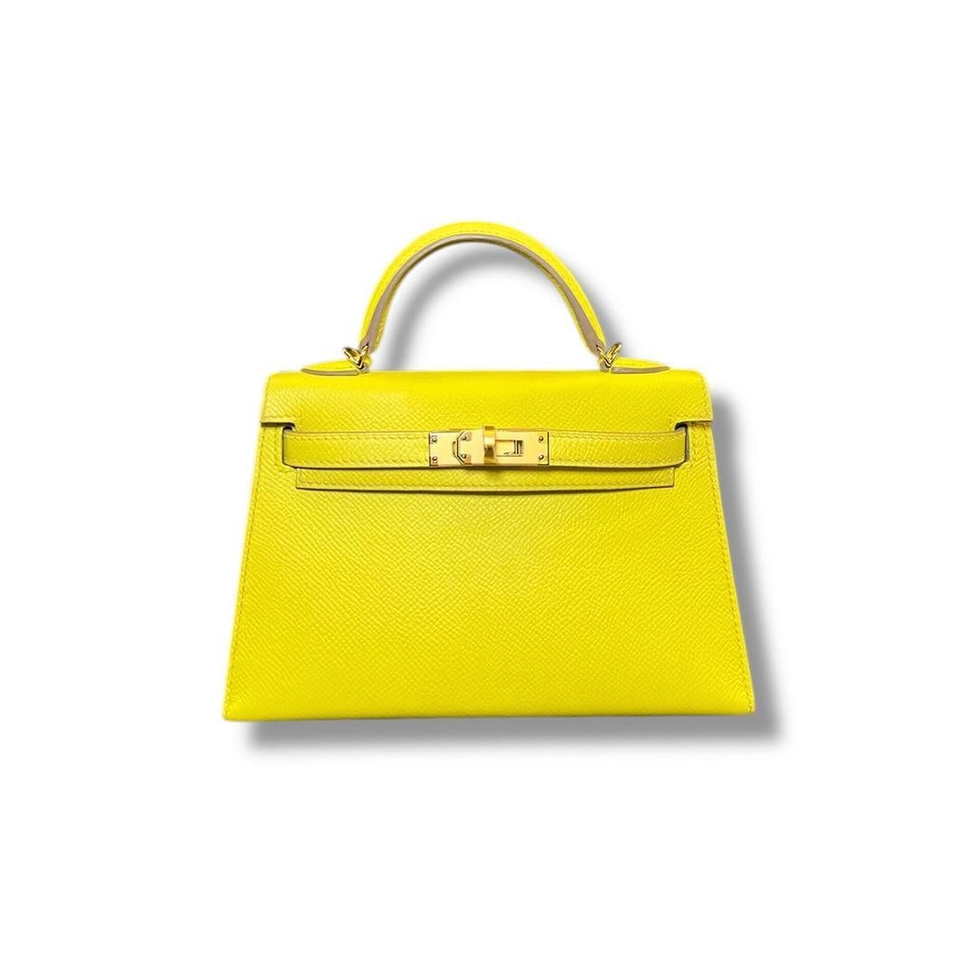 Jewels Aficionado propose un Hermès Lime Mini Kelly 20 Sellier en cuir d'Epsom qui est une pièce de déclaration vibrante. Sa teinte jaune audacieuse, associée à des ferrures dorées, ajoute une touche de sophistication ludique à cette silhouette