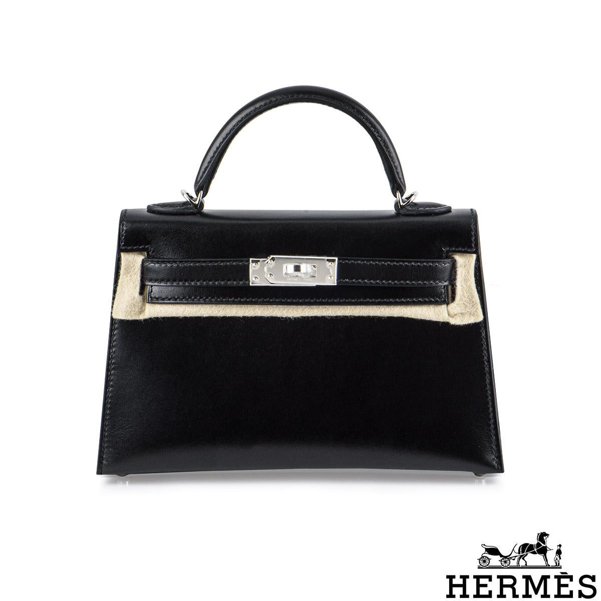 An exquisite Hermès Kelly II Sellier Mini 20cm handbag. The noir box leather bag is detailed with palladium hardware. The exterior of this Kelly Mini features a Sellier style in veau box leather. It has a front toggle closure, a single rolled handle