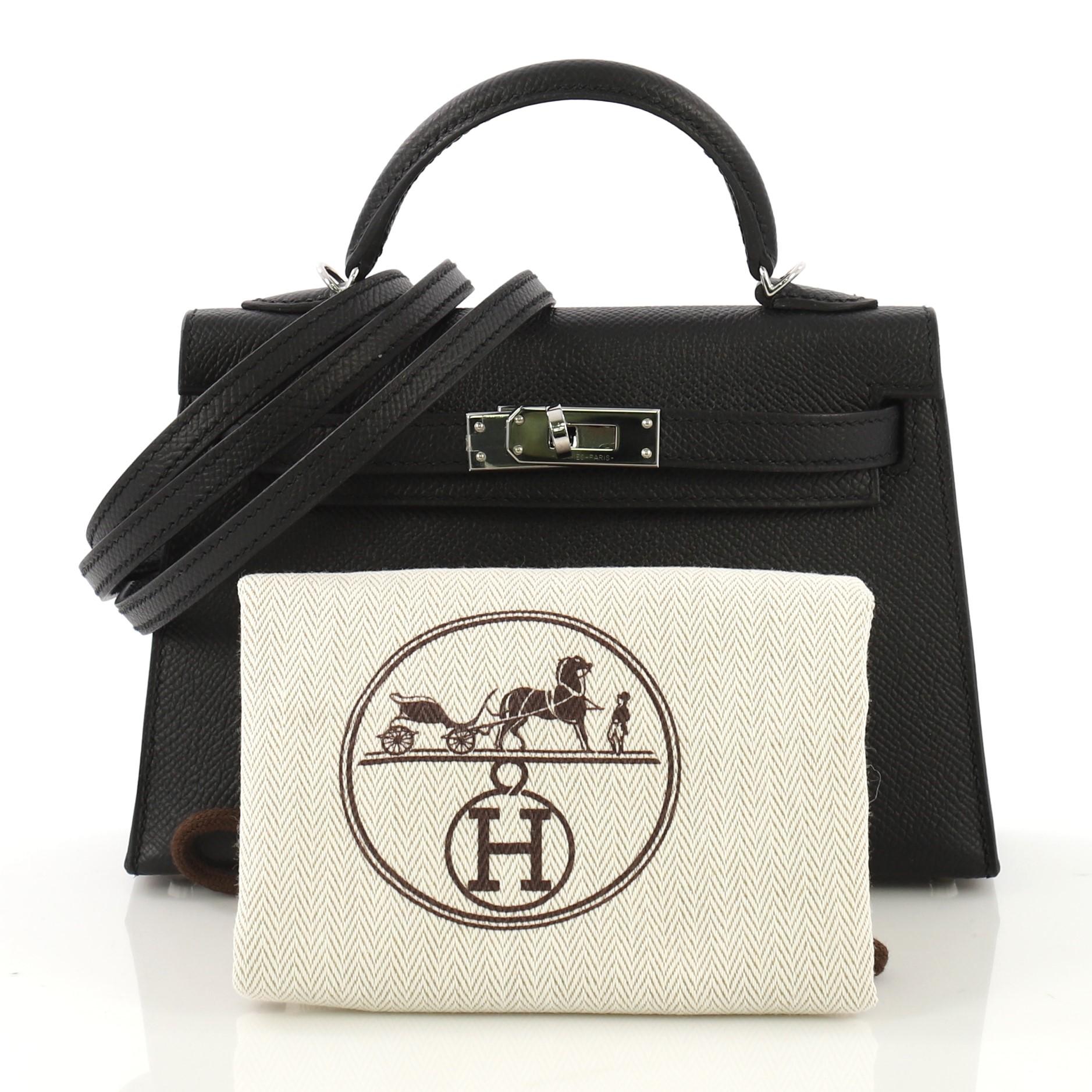This Hermes Kelly Mini II Handbag Noir Epsom with Palladium Hardware 20, crafted in Noir black Epsom leather, features a single rolled top handle, frontal flap, and palladium hardware. Its turn-lock closure opens to a Noir black Agneau leather
