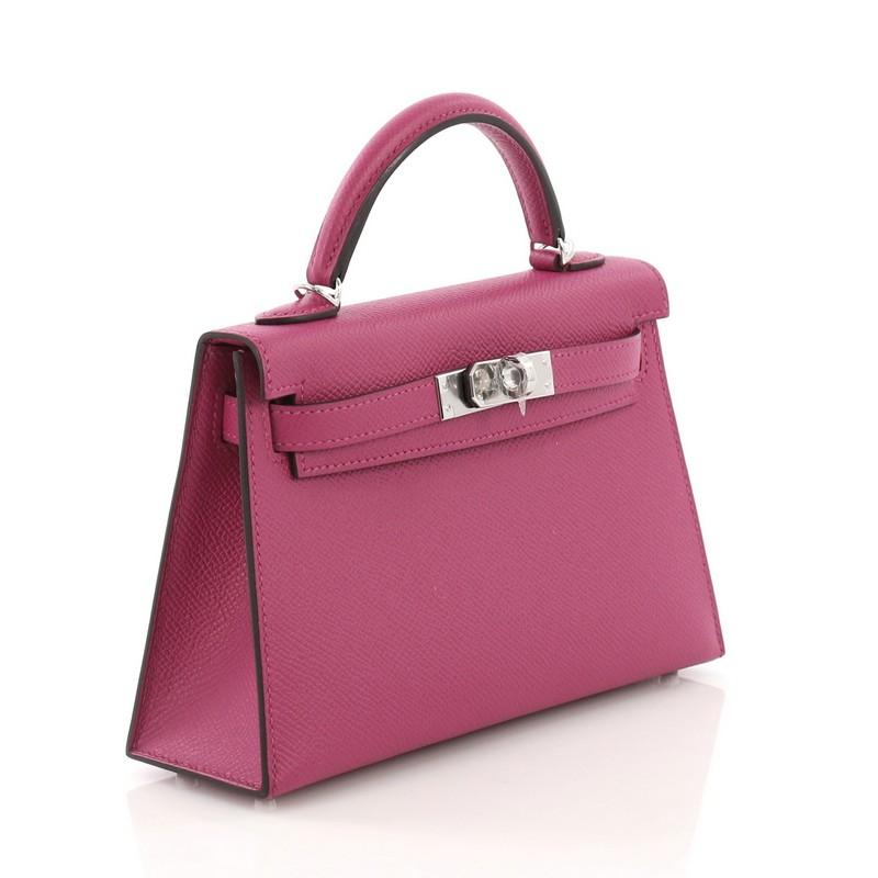 This Hermes Kelly Mini II Handbag Rose Pourpre Epsom with Palladium Hardware 20, crafted in Rose Pourpre Epsom leather, features a single rolled top handle, frontal flap, and palladium hardware. Its turn-lock closure opens to a Rose Pourpre Agneau