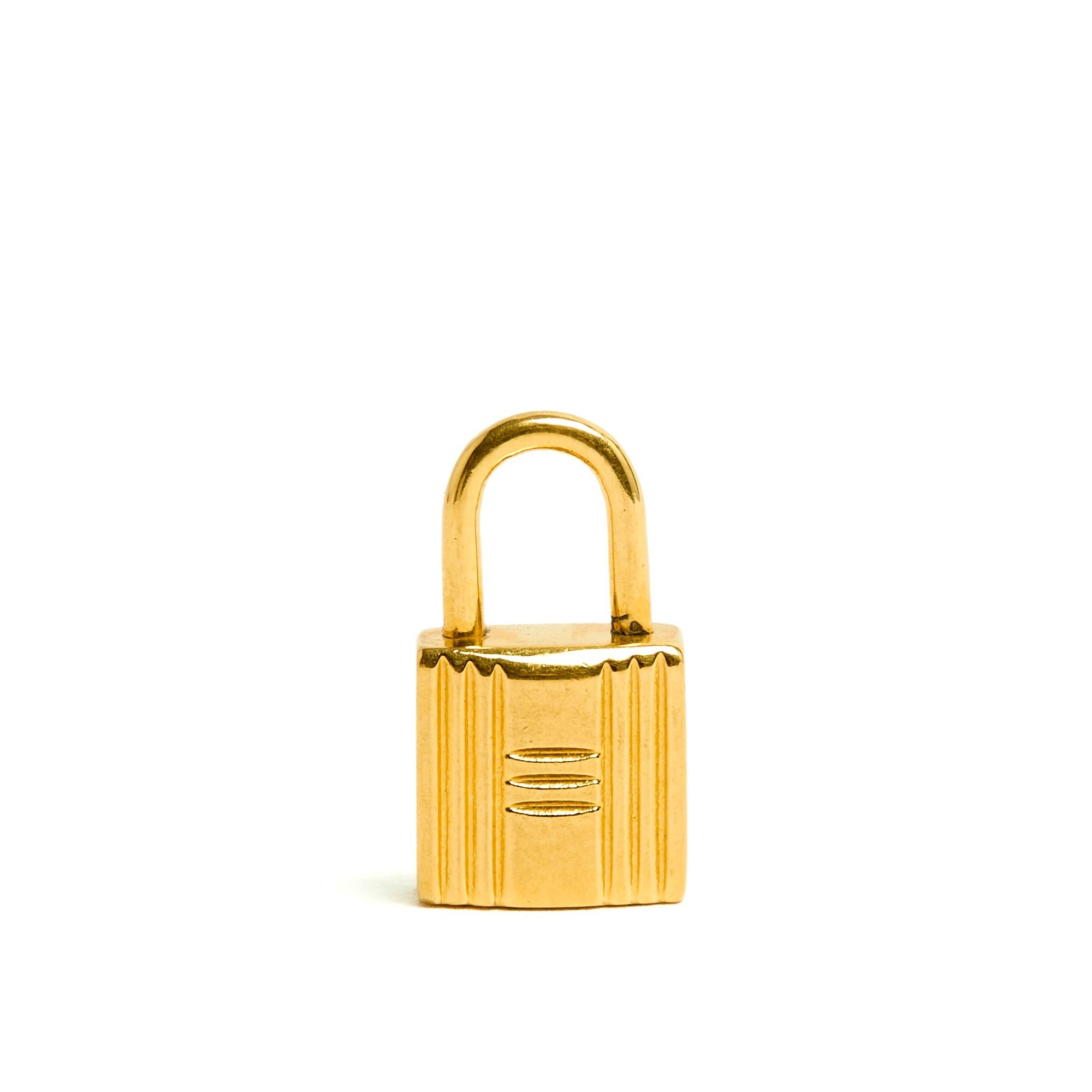 Pendentif Hermès en métal doré reprenant le motif du célèbre porte-clés Hermès généralement attribué au Kelly. Hauteur 1,9 cm x largeur 1 cm x épaisseur 0,6 cm. Le pendentif n'a jamais été porté, à mettre sur une petite chaîne de cou, chaîne de