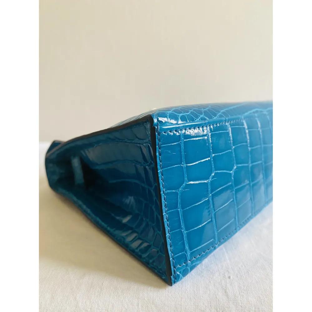Hermès Kelly petrol blue silver hardware alligator clutch
Alligator leather with silver tone hardware in good condition from 2013
Shows some slight opacity on the bottom of the bag 
No cites or invoice
Material: Exotic skins
Color: