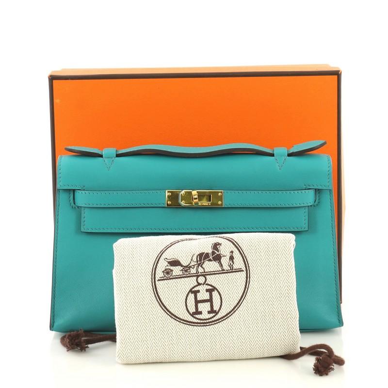 This Hermes Kelly Pochette Swift, crafted in Bleu Paon blue Swift leather, features a frontal flap, top flat handle, and gold hardware. Its turn-lock closure opens to a Bleu Paon blue Swift leather interior with slip pocket. Date stamp reads: X