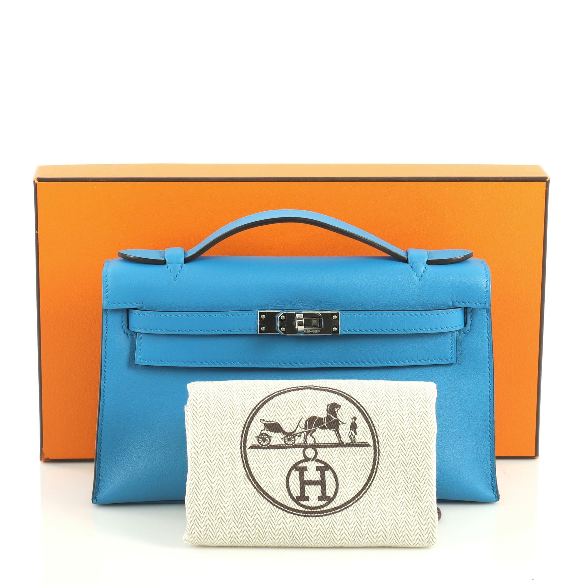 This Hermes Kelly Pochette Swift, crafted in Bleu Zanzibar blue Swift leather, features top flat handle, frontal flap, and palladium hardware. Its turn-lock closure opens to a Bleu Zanzibar blue Swift leather interior with slip pocket. Date stamp