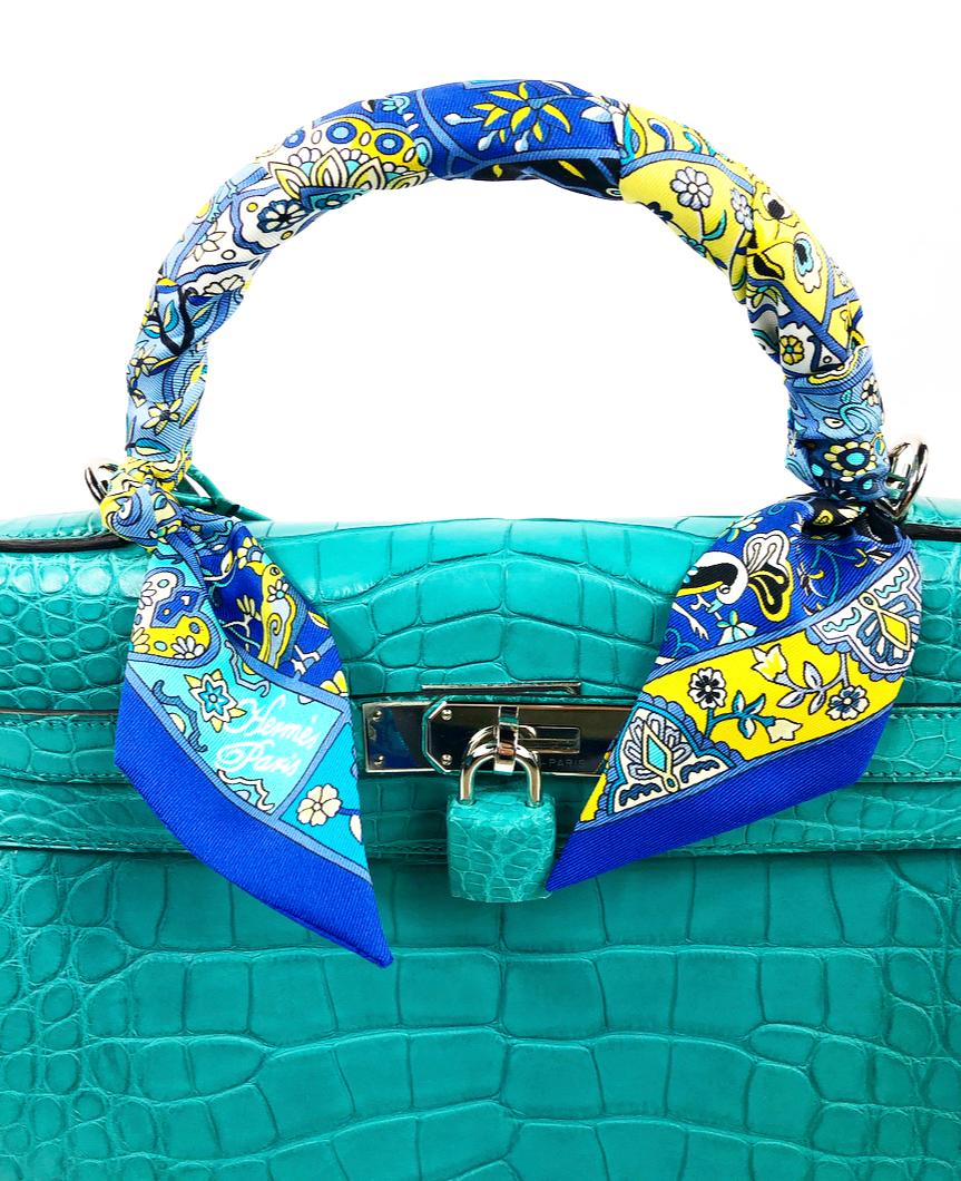 
Hermès Kelly Retourne 32 Blue Atoll Alligator Mississippiensis Mat Handbag w/ Scarf

Product details:
Silver- plated hardware 
Single rolled top handle
Protective feet at base
Detachable flat strap
Includes: scarf, lock, 2 keys, dust bag, box and