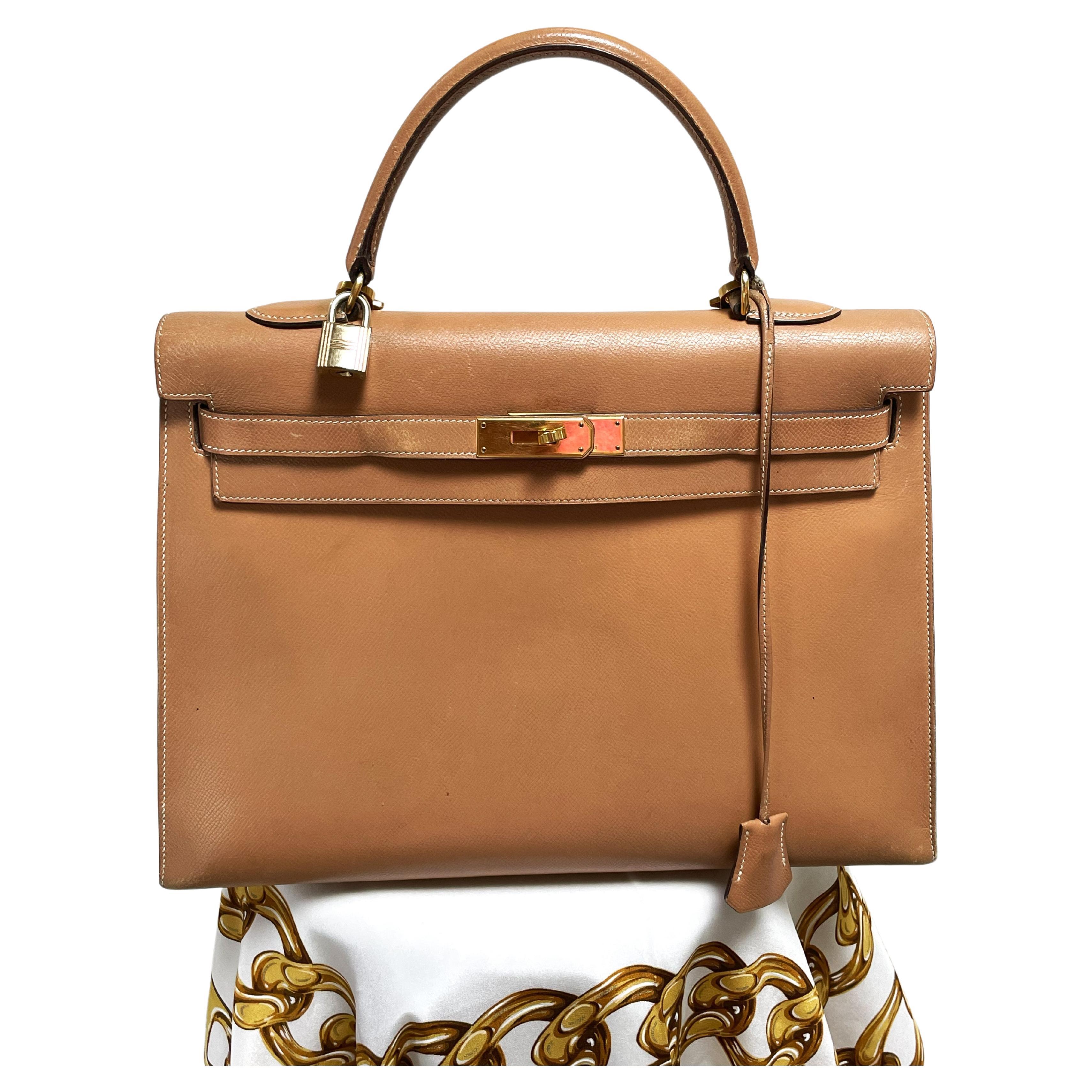 Un precioso bolso Hermès Kelly Sellier de 35 cm en piel Courchevel dorada   (Fabricado en Francia).
La piel Courchevel dorada se complementa con herrajes dorados y pespuntes tonales. Presenta un cierre basculante delantero con dos correas estampadas
