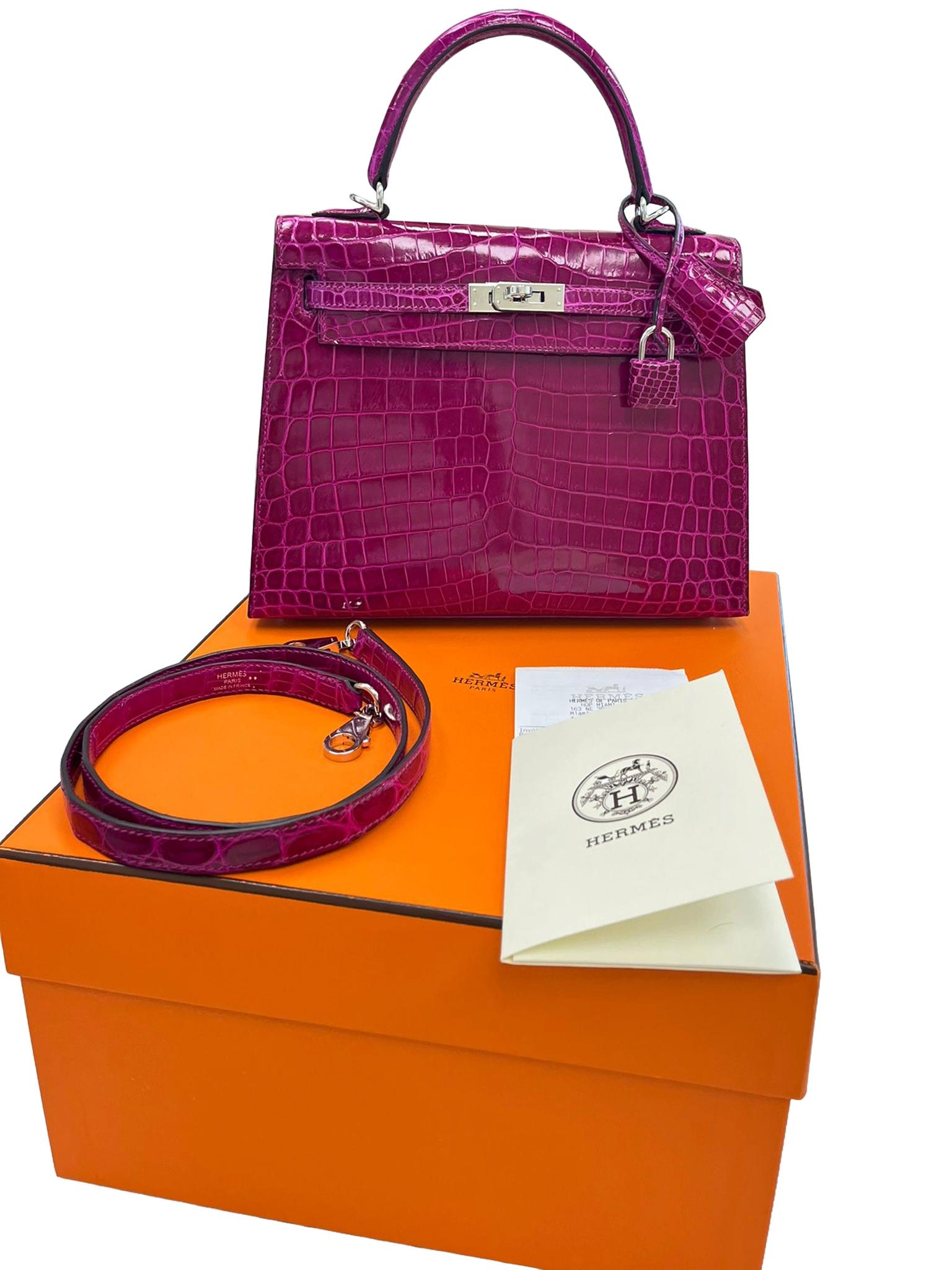 Ce Kelly, dans le style Sellier, est en cuir de crocodile Niloticus brillant Rose Pourpre avec des accessoires en palladium. Il présente des coutures ton sur ton, un rabat avant, deux sangles avec fermeture à genouillère centrale, une clochette avec
