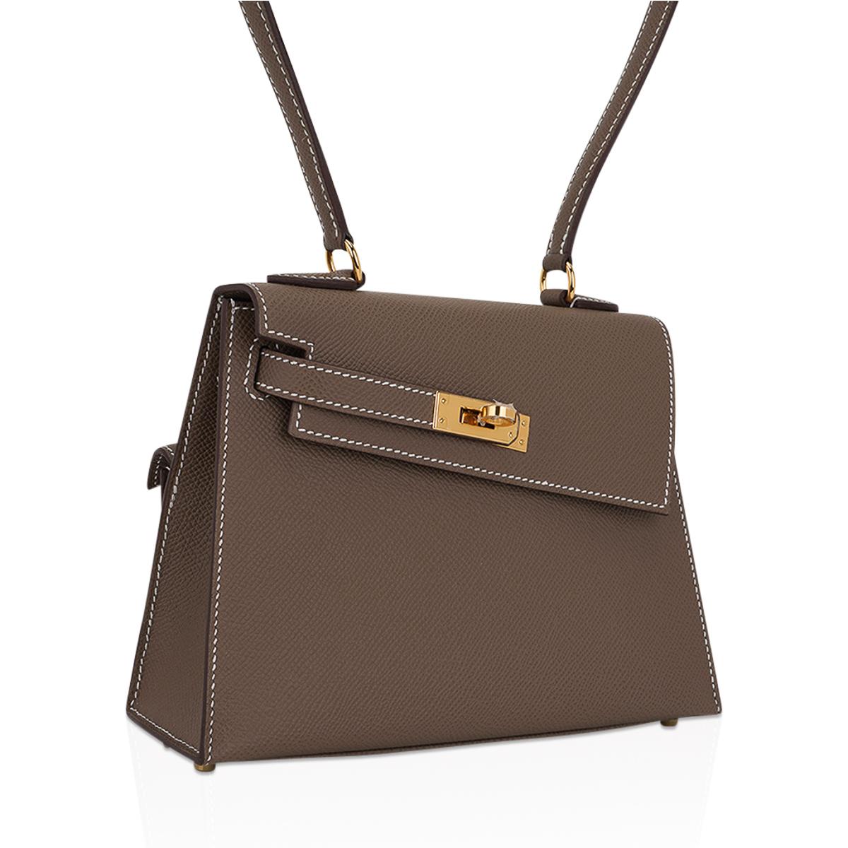 Mightychic offers a very Limited Edition Hermes Kelly 20 Sellier En Desordre featured in Etoupe.
Part of the disorder series, this is a Kelly with a twist.
The front flap is attached at an angle with one sangle and touret.
The back has an outer