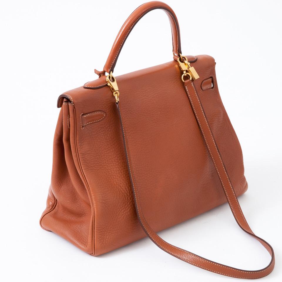 Kelly 35 vintage Taurillon Clemence bag in camel leather, gold metal attributes, flap with iconic clasp, handle for a hand carried, shoulder strap for a shoulder, a zipped pocket and two patch pockets inside. Sold with dustbag, key and padlock. Year
