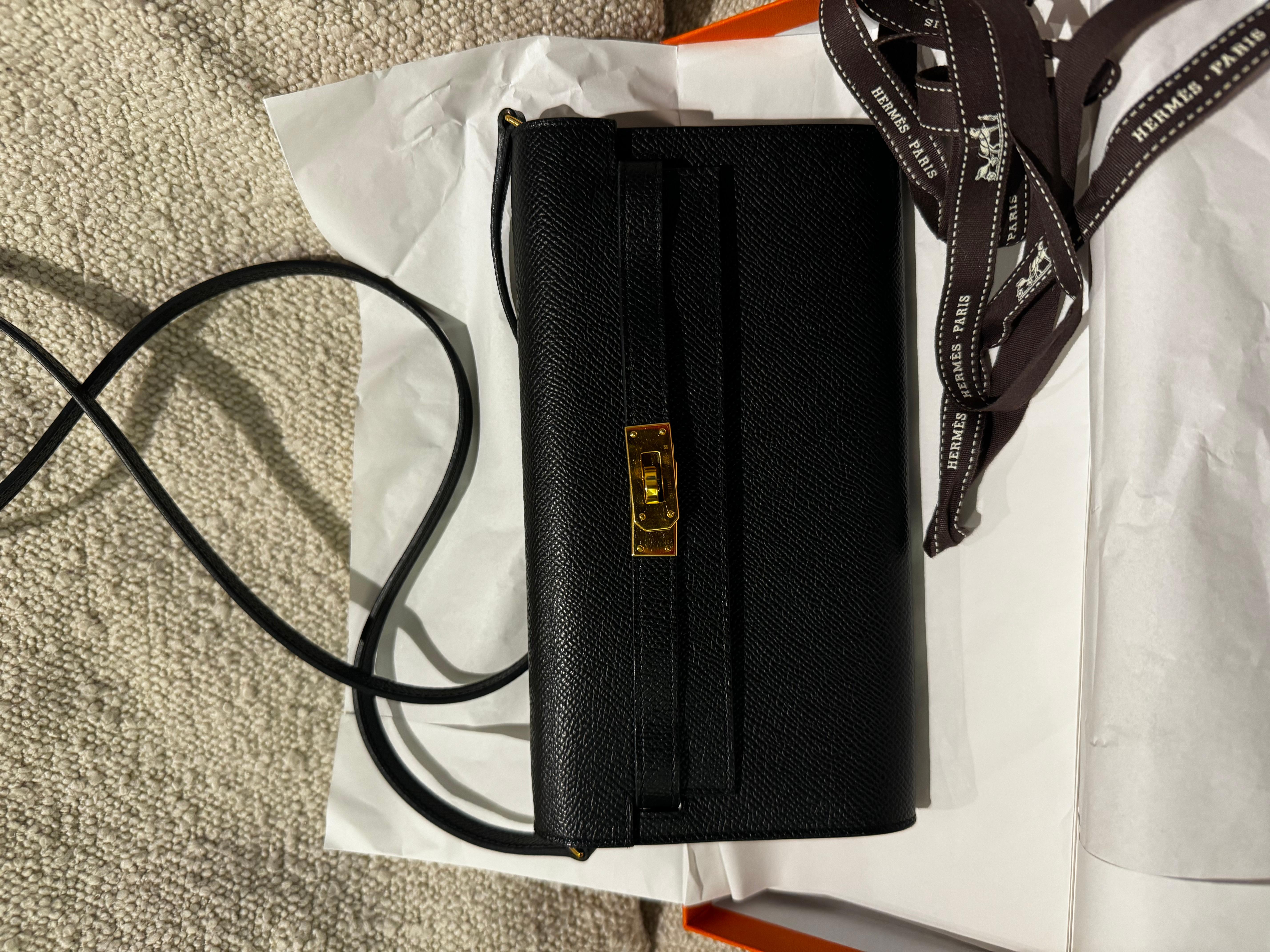 Hermes kelly to go en noir epsom avec des ferrures dorées et une longue lanière pour le porter en bandoulière. Il peut être utilisé comme pochette ou comme sac à bandoulière. Très pratique et chic. Utilisé peu de fois, quelques signes dans le