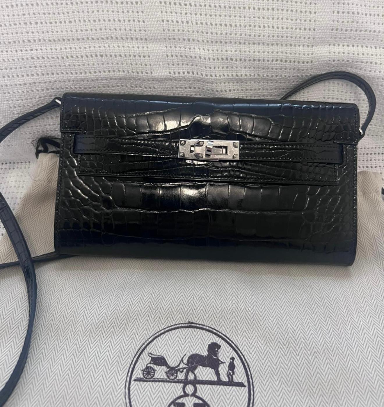 Hermes Kelly Wallet To Go is in Black Shiny Alligator Mississippiensis leather with palladium hardware, two straps with front kelly closure and removable crossbody strap. Stickers on hardware. 

The interior is lined with Black chevre leather and