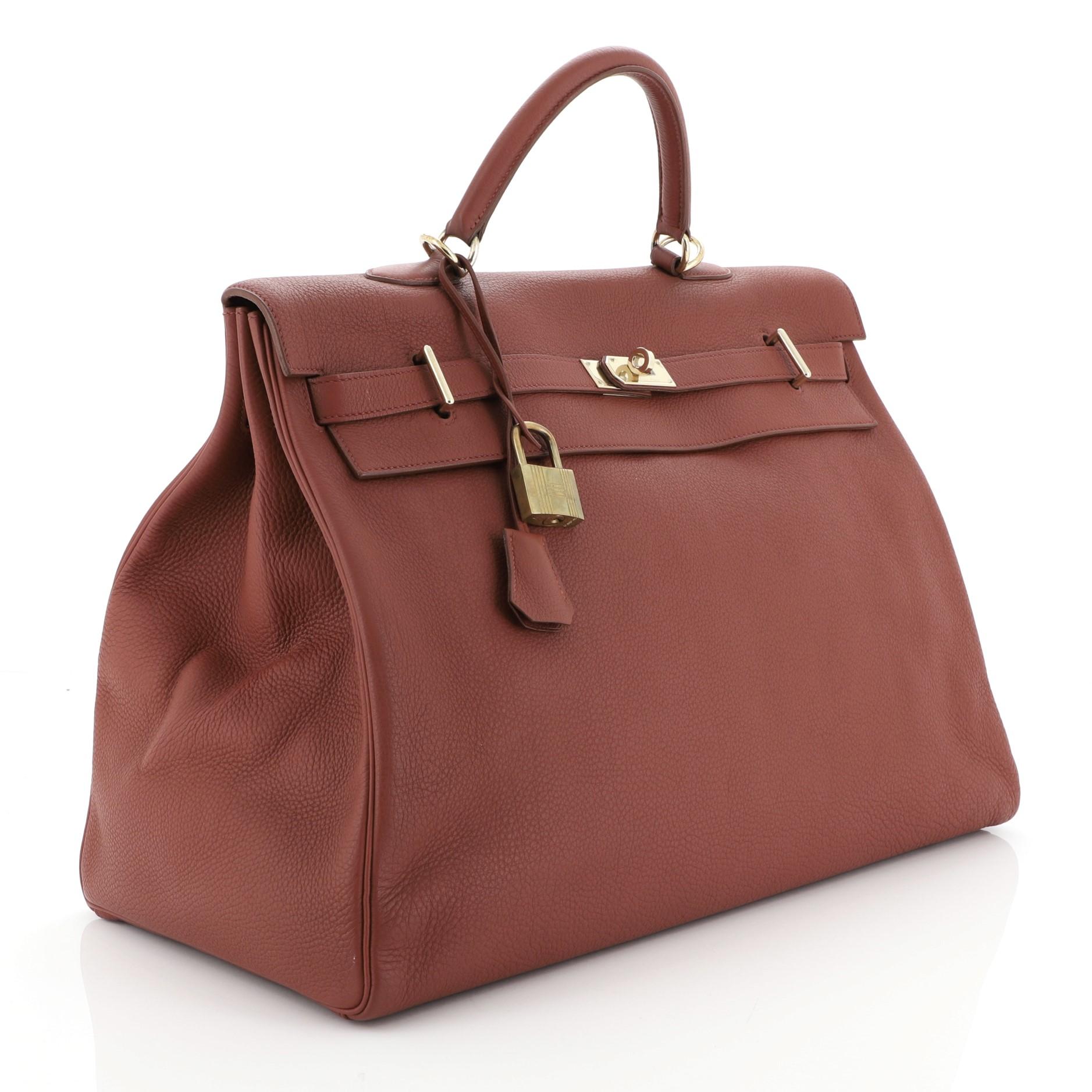 This Hermes Kelly Travel Handbag Brique Togo with Gold Hardware 50, crafted in Brique Togo leather, features a single top handle, protective base studs and gold hardware. Its turn-lock closure opens to a Brique Chevre leather interior with zip and