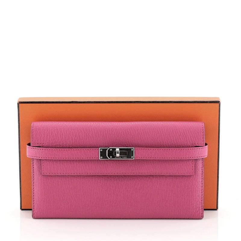 This Hermes Kelly Trifold Wallet Chevre Mysore Long, crafted in Rose Shocking pink Chevre Mysore leather, features palladium hardware. Its turn-lock closure opens to a Rose Shocking pink Chevre Mysore leather interior multiple card slots and flap