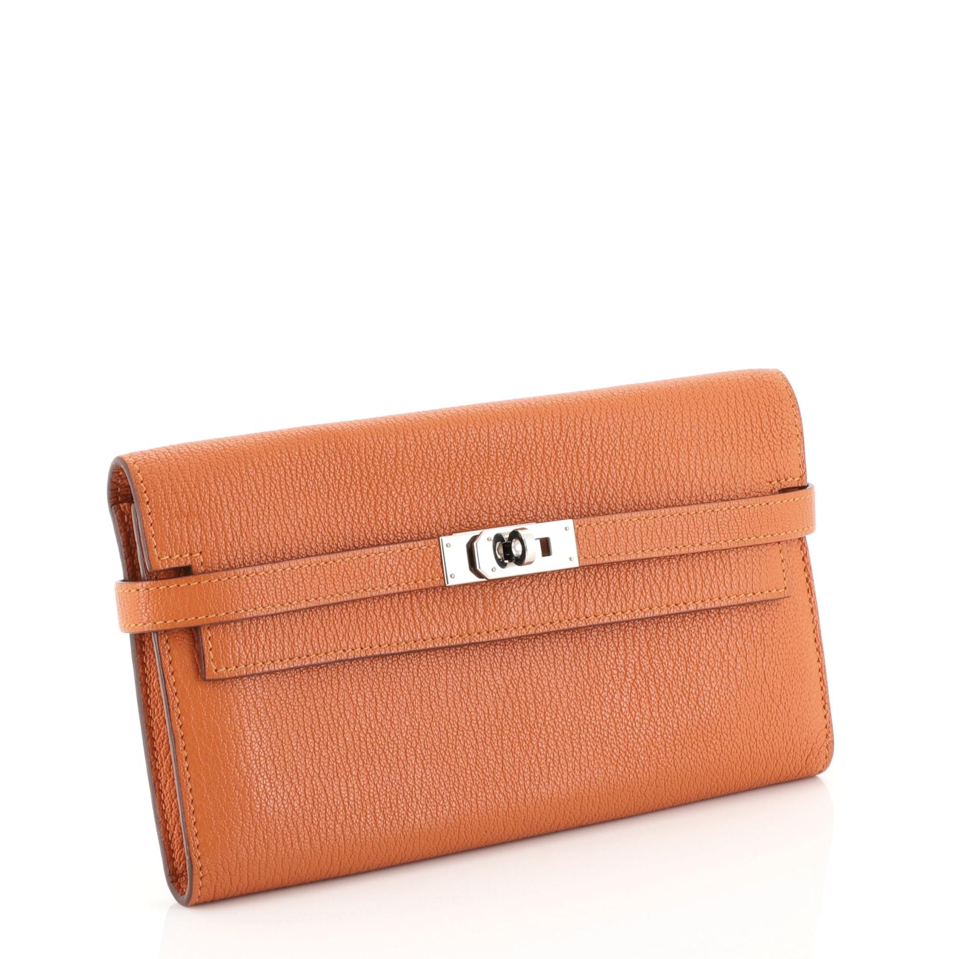 This Hermes Kelly Wallet Chevre Mysore Long, crafted in Orange H orange Chevre Mysore leather, features palladium hardware. Its turn-lock closure opens to an Orange H orange Chevre Mysore leather interior with middle zip compartment, slip pocket and