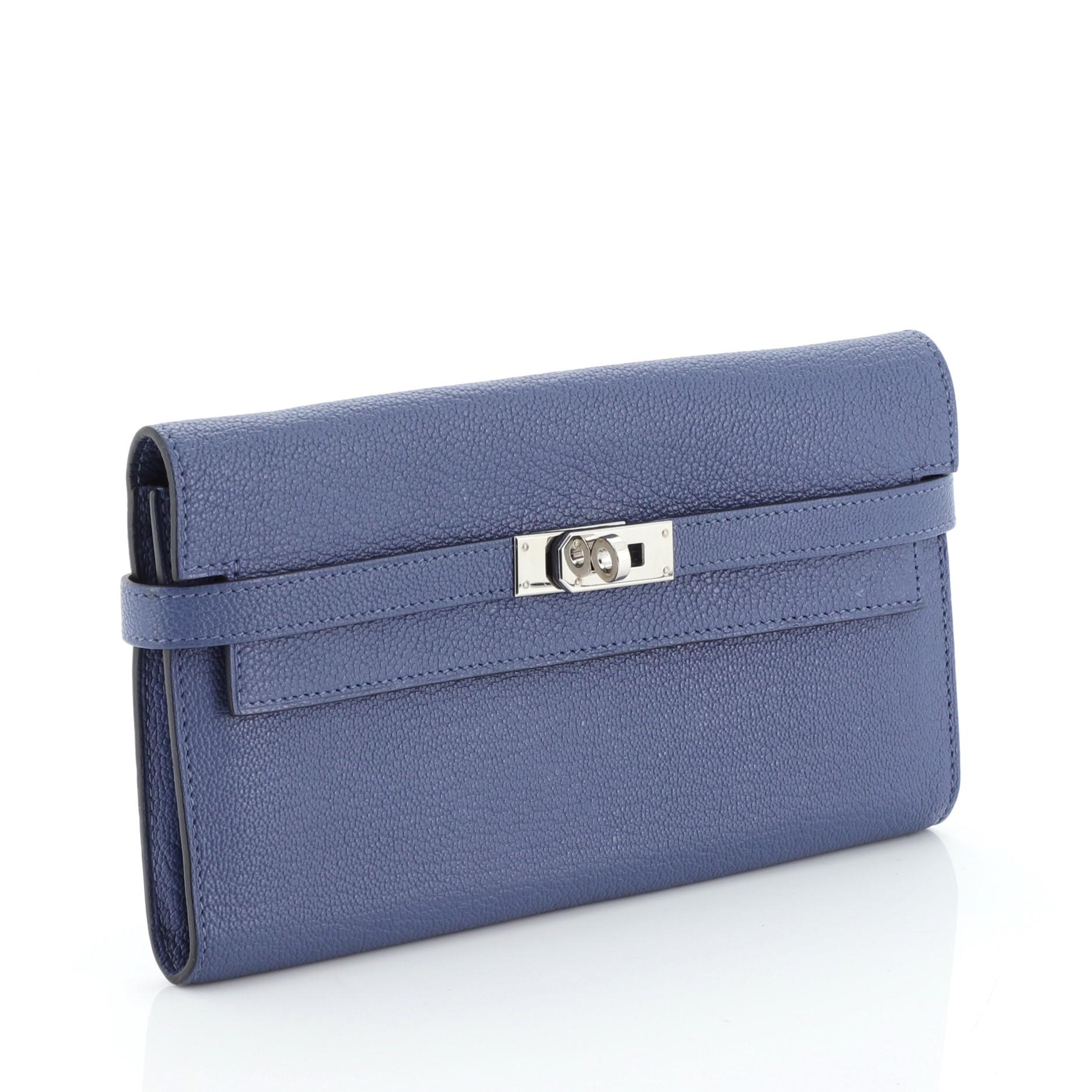 This Hermes Kelly Wallet Chevre Mysore Long, crafted in Bleu Brighton blue Chevre Mysore leather, features palladium hardware. Its turn-lock closure opens to a Bleu Brighton blue Chevre leather interior with middle zip compartment, slip pocket and