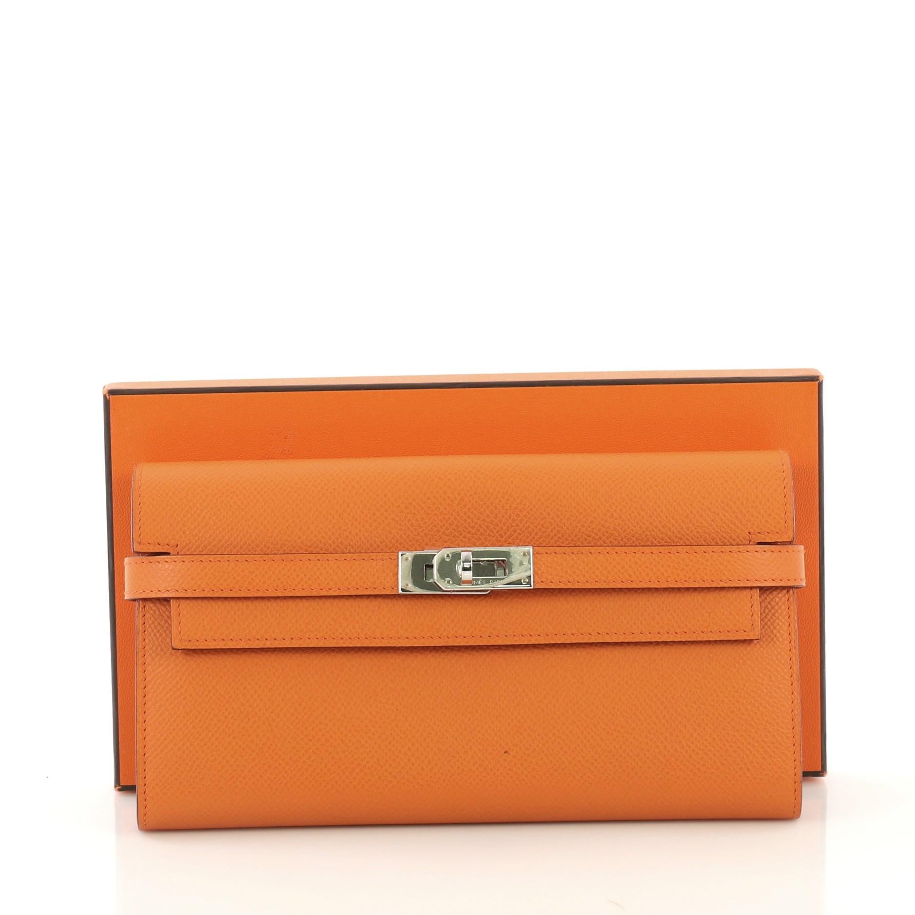 This Hermes Kelly Wallet Epsom Long, crafted in Orange H orange epsom leather, features palladium hardware. Its turn-lock closure opens to an Orange H orange epsom leather interior with middle zip compartment, slip pocket and multiple card slots.