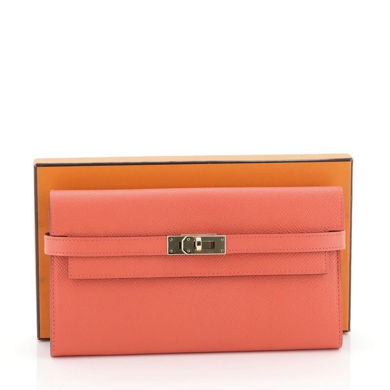 This Hermes Kelly Wallet Epsom Long, crafted in Rose Jaipur orange Epsom leather, features gold hardware. Its turn-lock closure opens to a Rose Jaipur orange Epsom leather interior with middle zip compartment, slip pocket and multiple card slots.