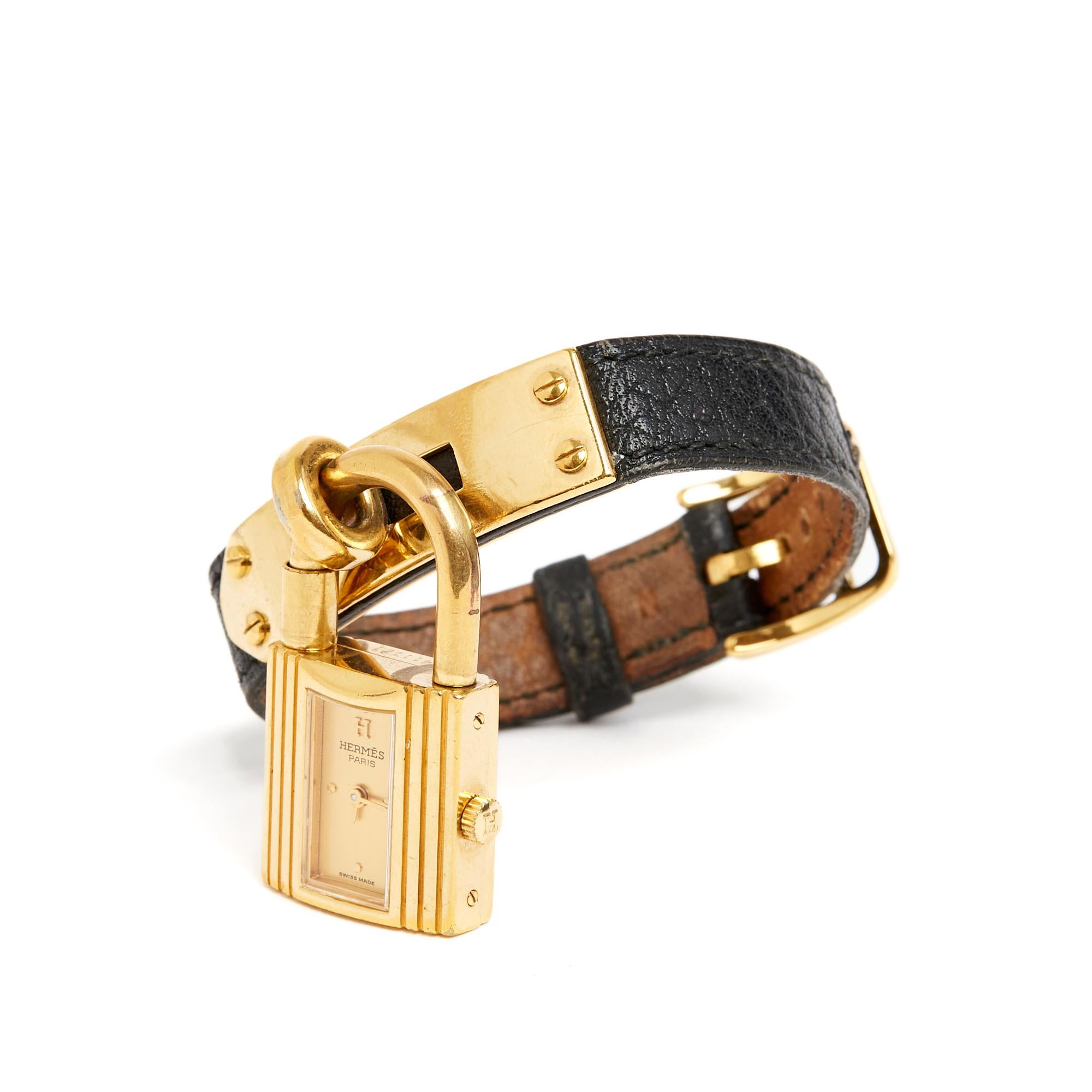 Hermès model Kelly watch in gold-plated metal, satin-finish gold background, indexes at 12 o'clock, 3 o'clock, 6 o'clock and 9 o'clock in gilded stud in the Dog Collar style, quartz movement (battery), black grained leather strap, gold-plated metal