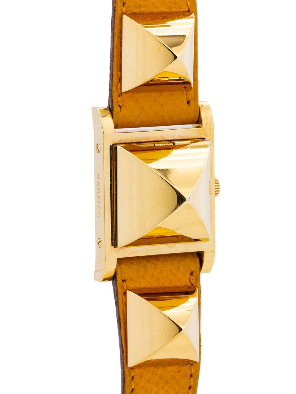 
Hermes “Medor” cabochon shape pyramid design lady’s gold plate wristwatch with stainless steel case back. This eye catching and recognizable design features 2 pyramid shaped decorative elements secured to original yellow Hermes strap with centered
