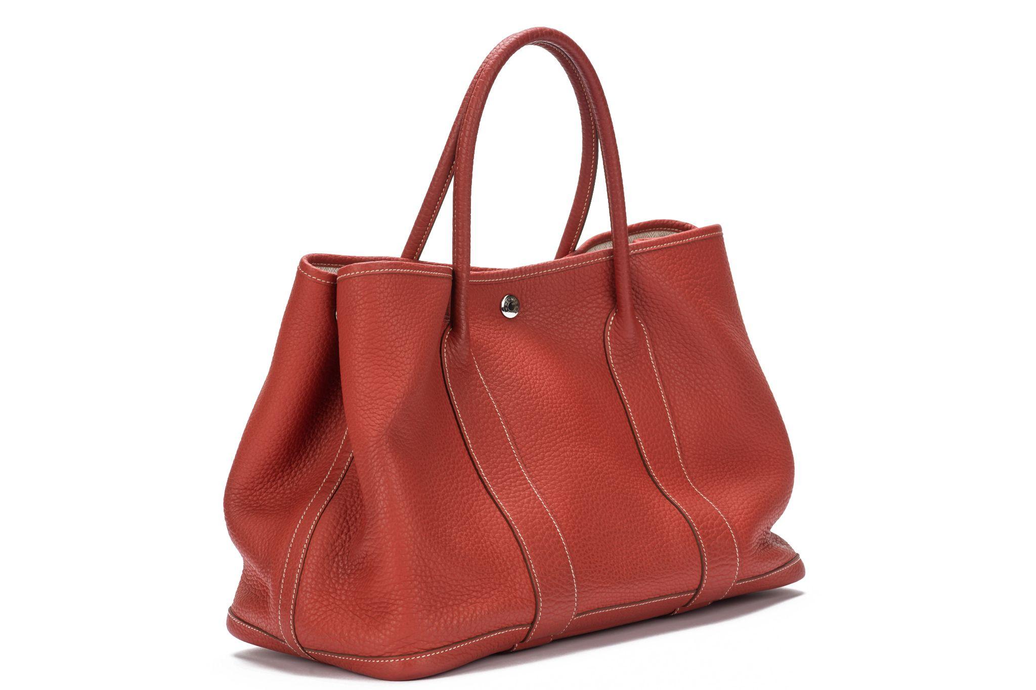 HERMÈS Garden Party bag crafted of negonda leather in the color sanguine. It's a smart bag which can be used on different occasions. The bag closes on top with a palladium hardware button and the interior is beige linen fabric. Date stamp O. The