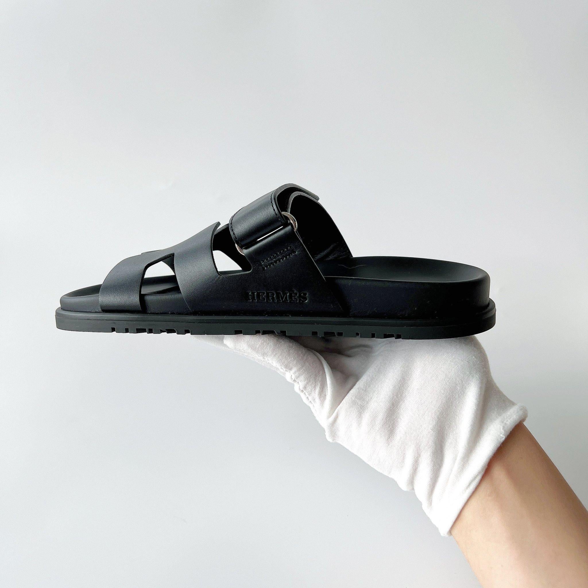 Cette magnifique paire de sandales Hermès Chypre entièrement noires. Femmes EU 38.5. La sandale est fabriquée en cuir de veau avec une semelle en caoutchouc. Neuf et non porté. Avec le reçu, la boîte et les sacs à poussière. 

Marque :
